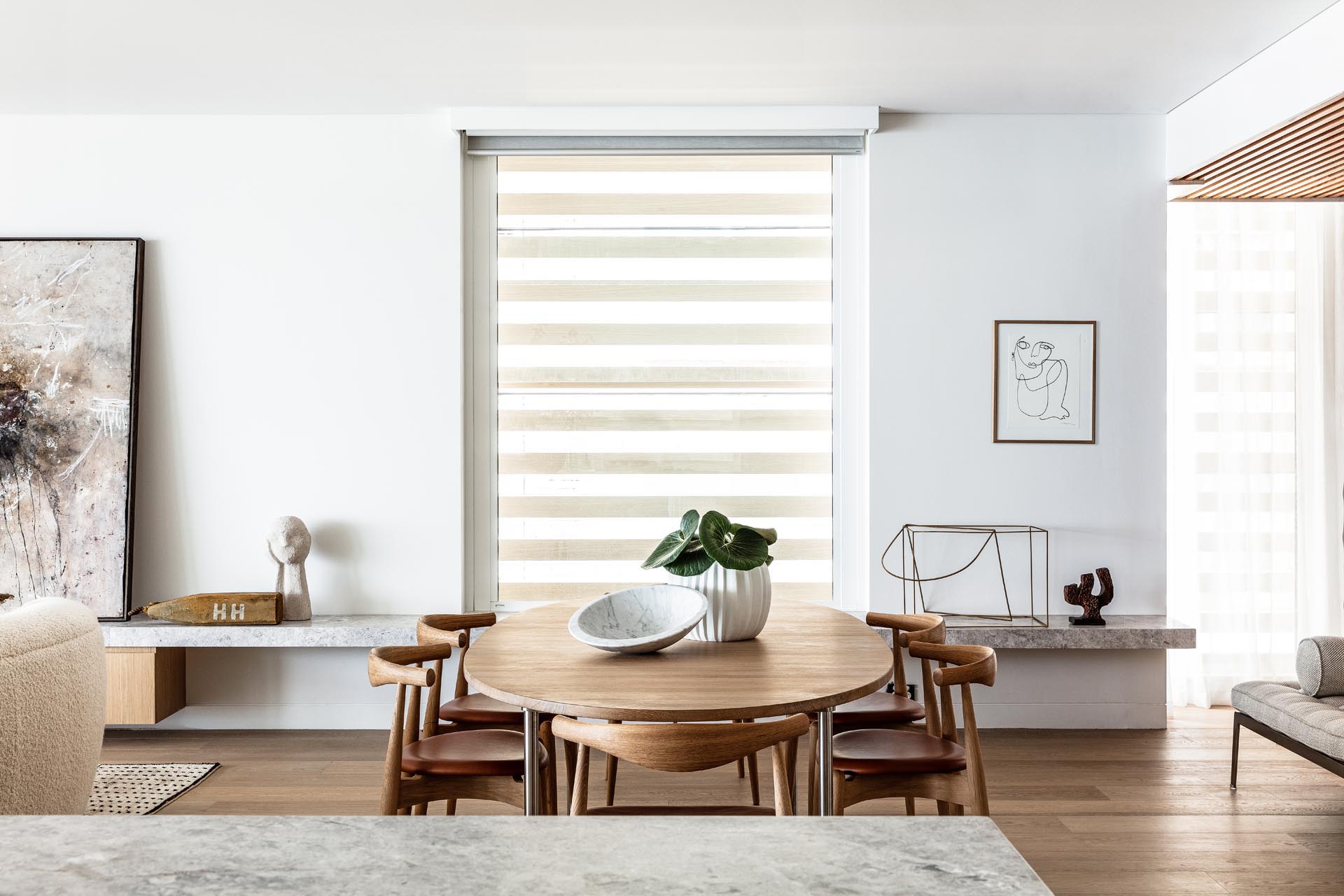 A modern open plan dining room with an oval dining table surrounded by chairs, all of which are made from wood.