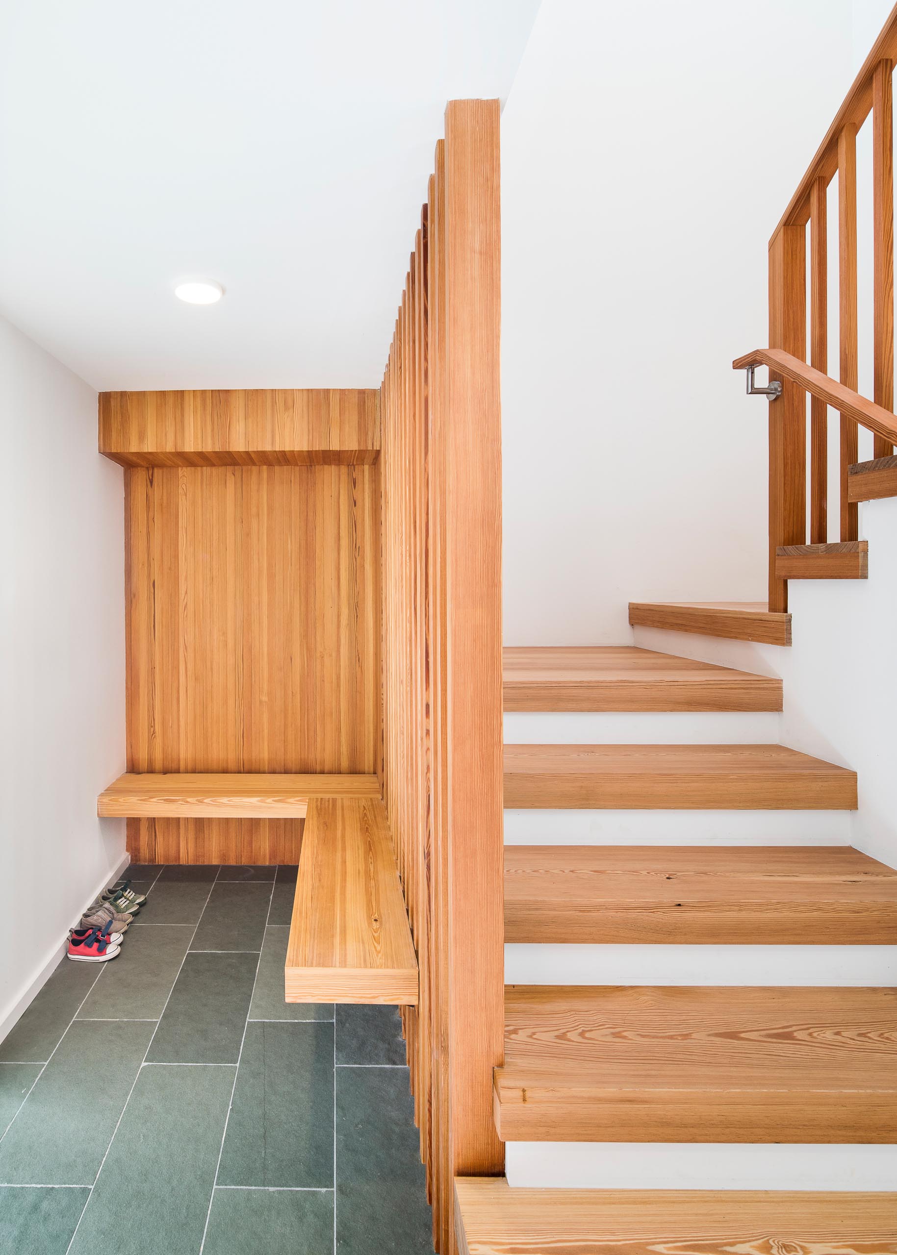 A floating wood entryway bench with gray tiles.