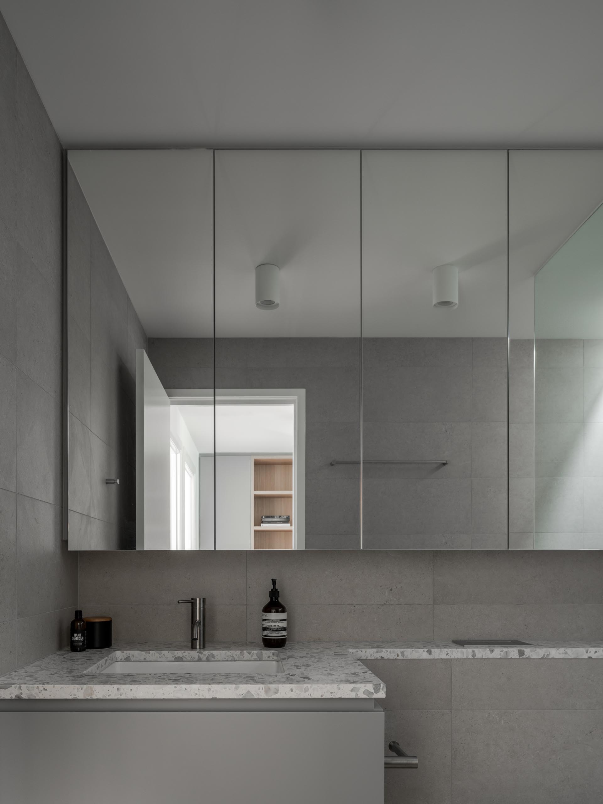 A gray bathroom with a white stone countertop.