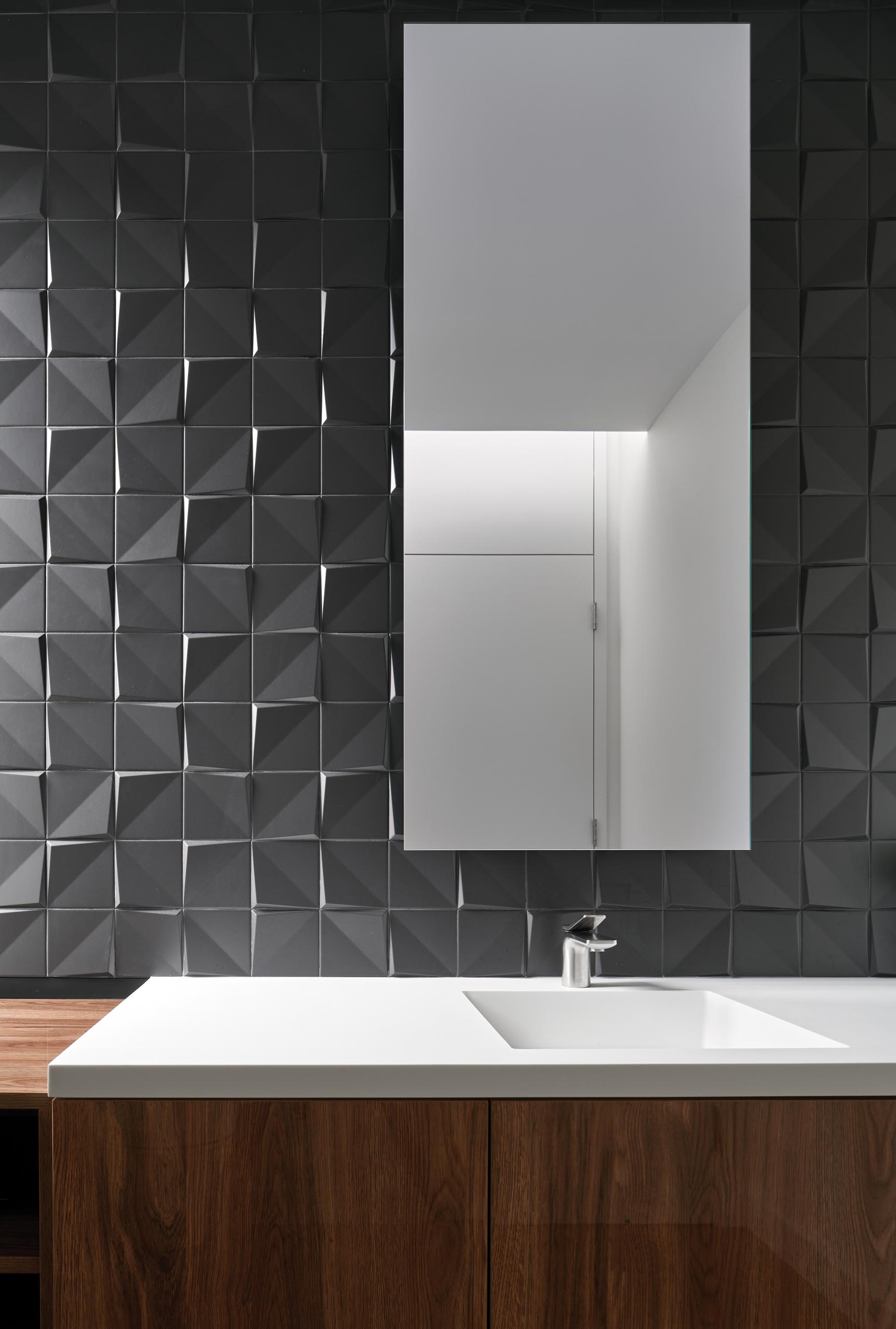 A modern grey and wood bathroom with 3-dimensional tiles that add texture to the wall.