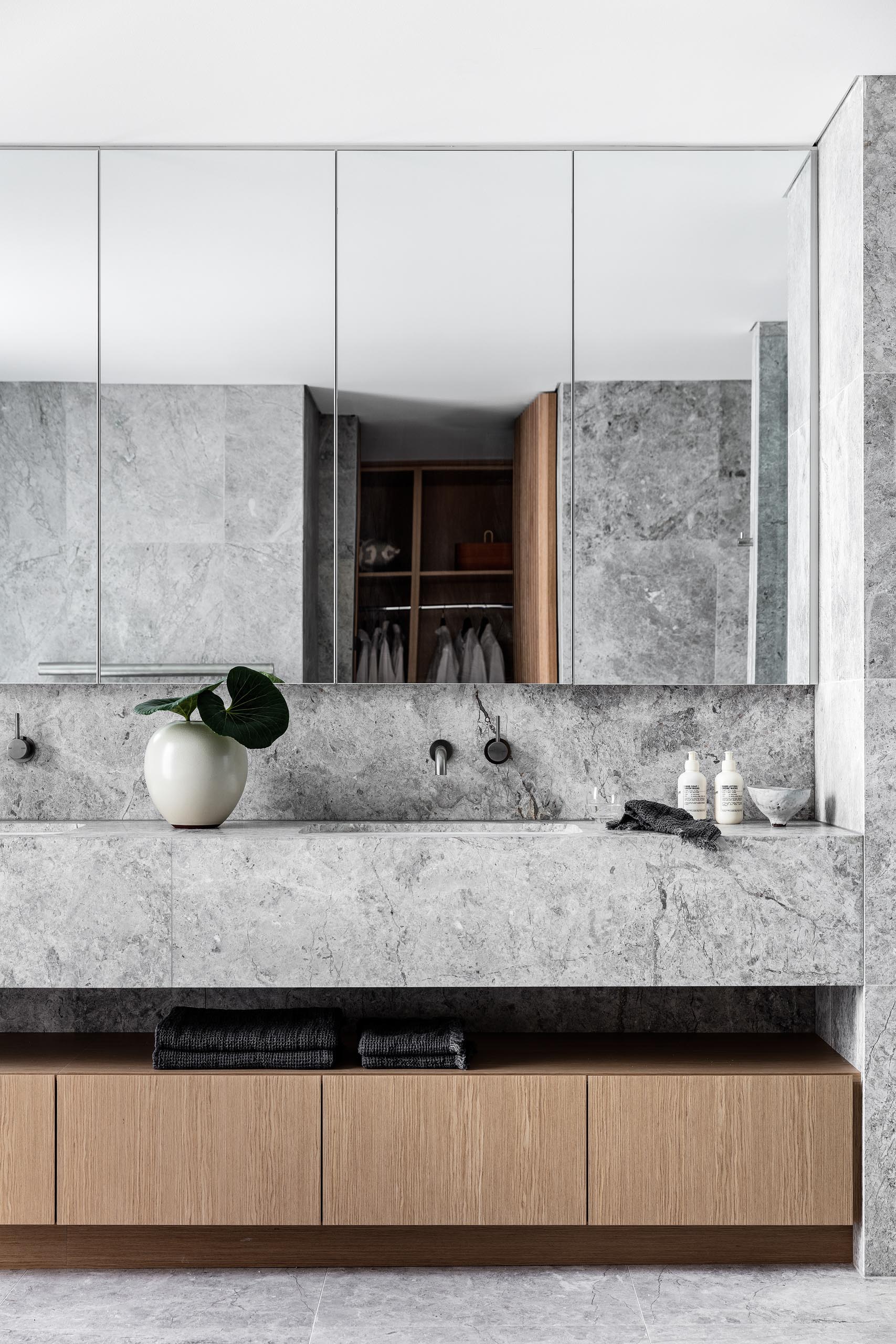 In this modern master bathroom, natural stone with a grey finish covers the walls and floors, as well as the vanity.
