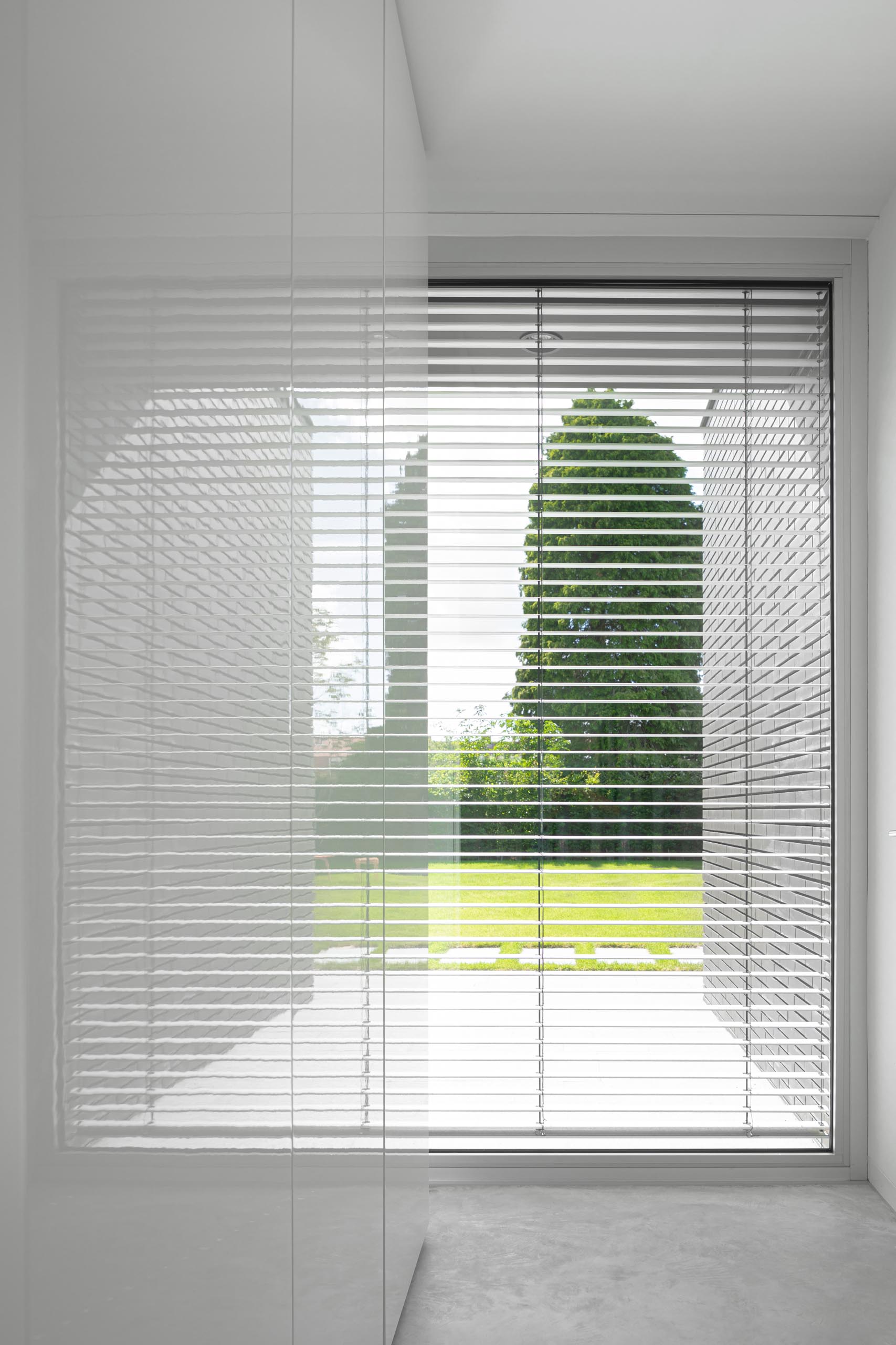 A window with white blinds and minimalist cabinets.