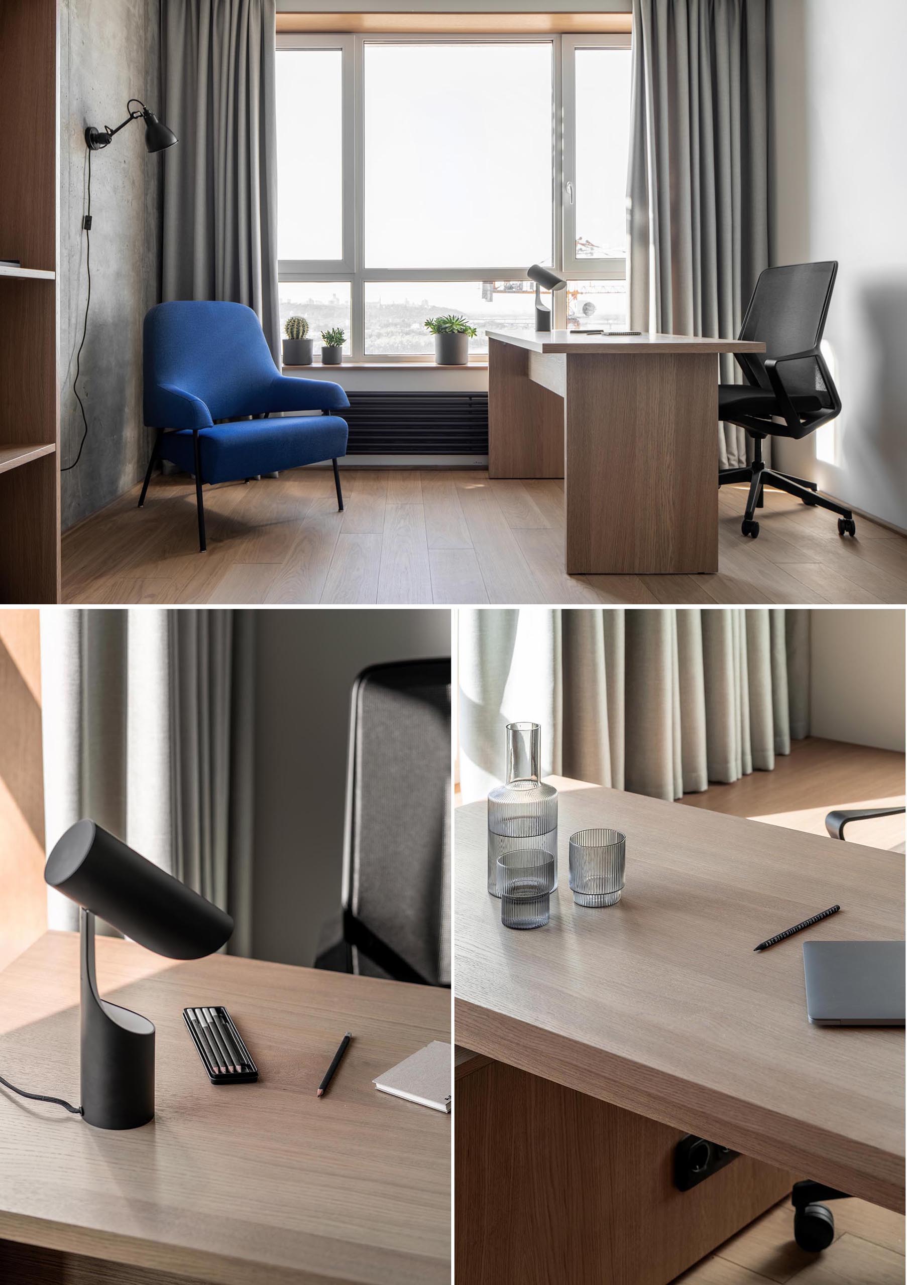 A modern home office with long curtains, a wood desk, a blue armchair, and concrete wall.