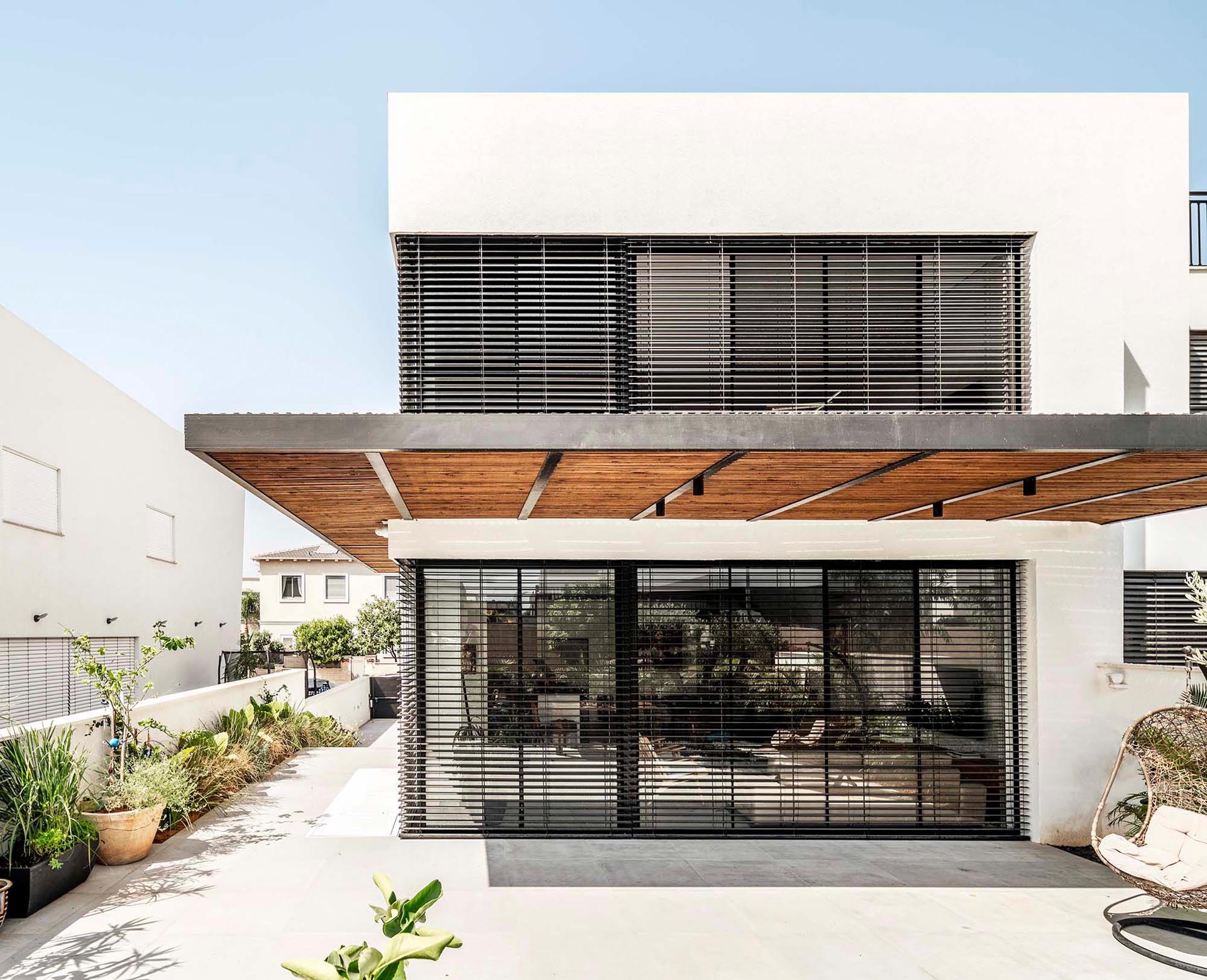 A modern home with a white facade, black window frames, and wood accents.