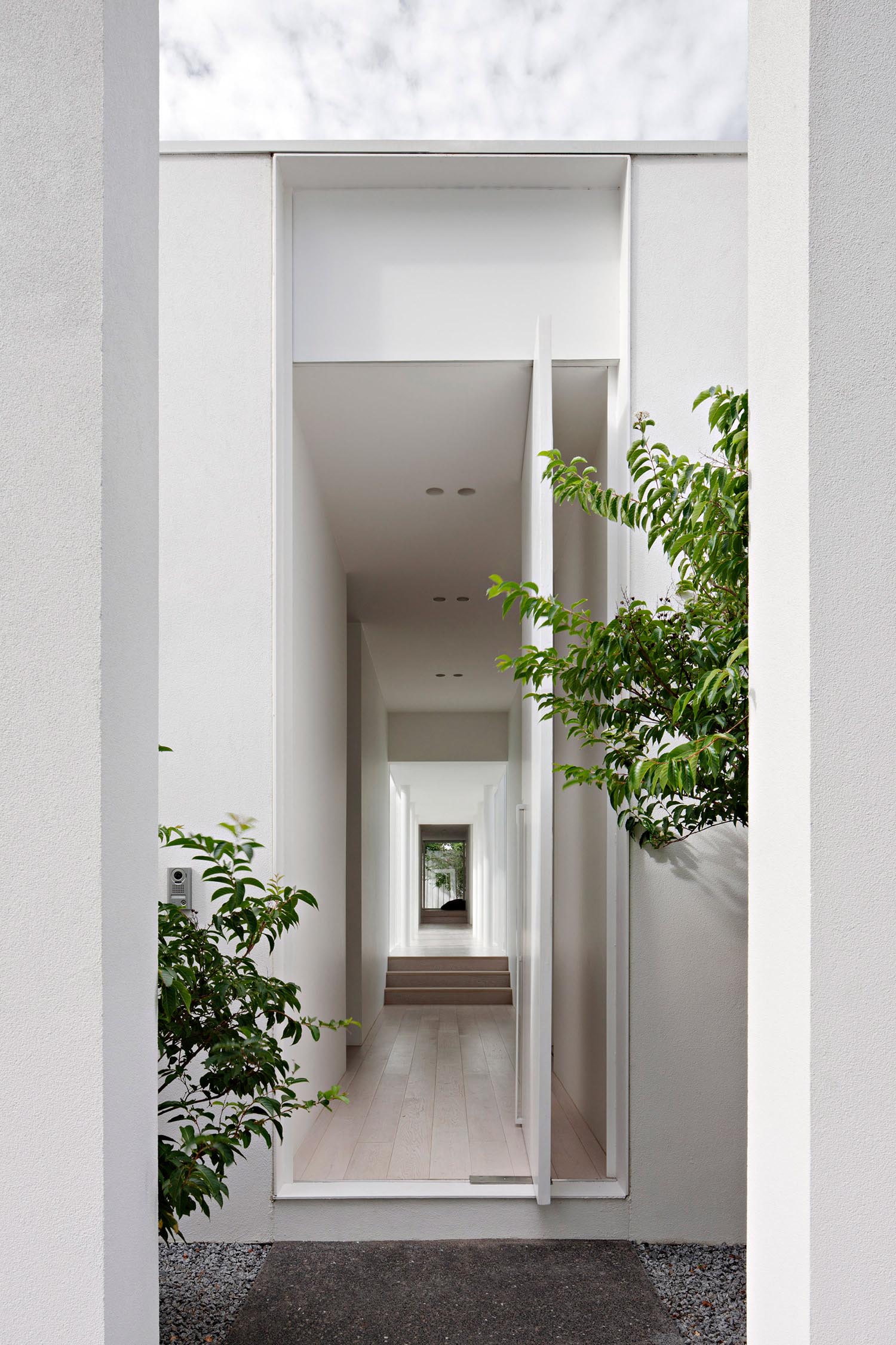 A modern house with a white exterior, that also has a pivoting white front door.