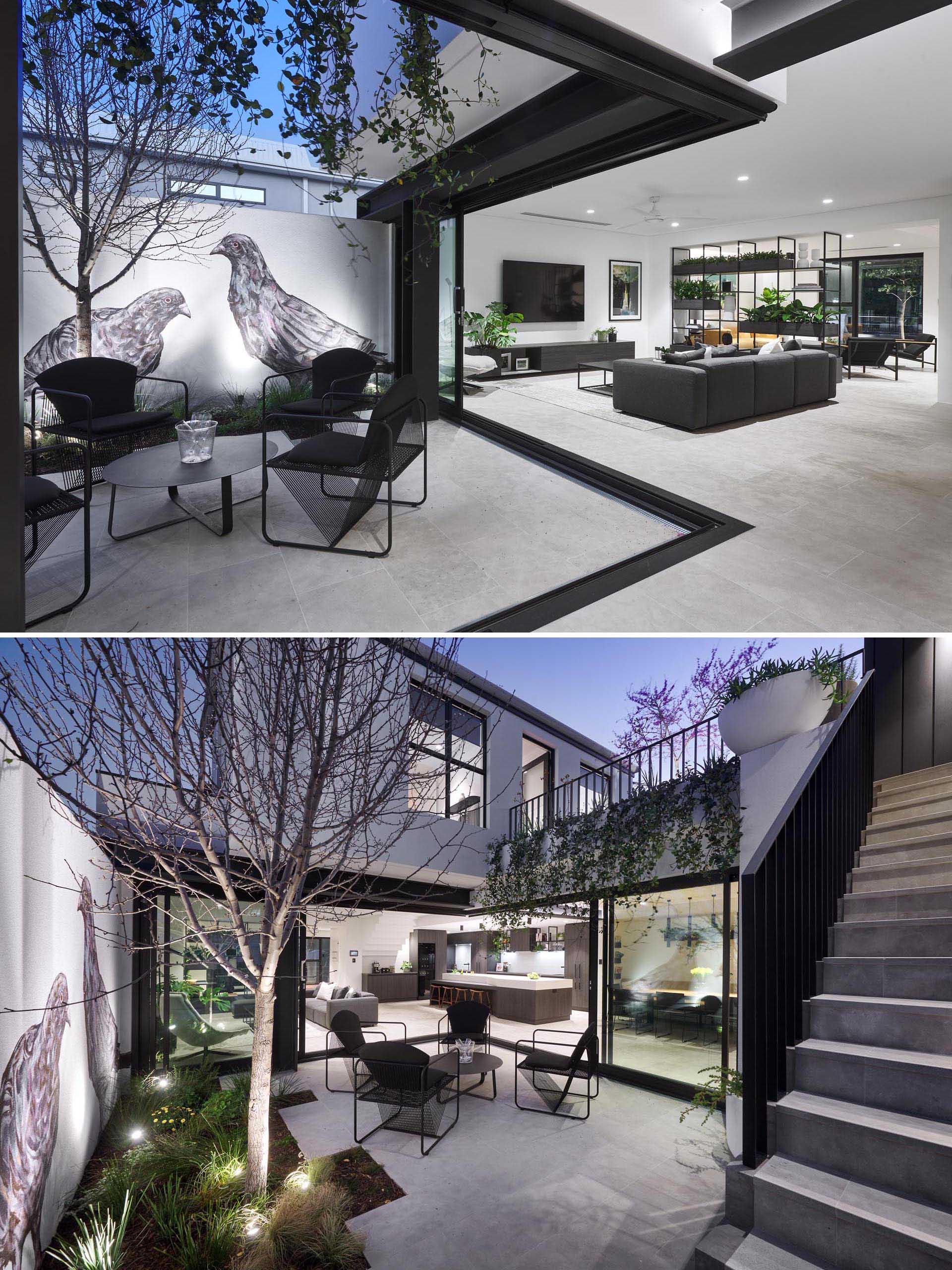 A modern house with a courtyard that's furnished with four sculptural chairs and a small round table. On the wall is a large mural of birds that adds an artistic touch to the space.