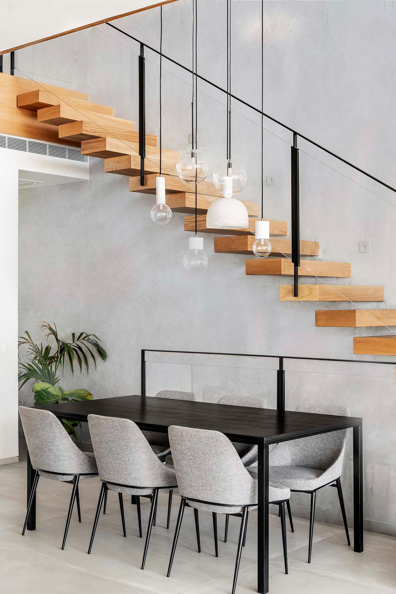 The dining room is furnished with a black table and light gray chairs, which also match the walls.