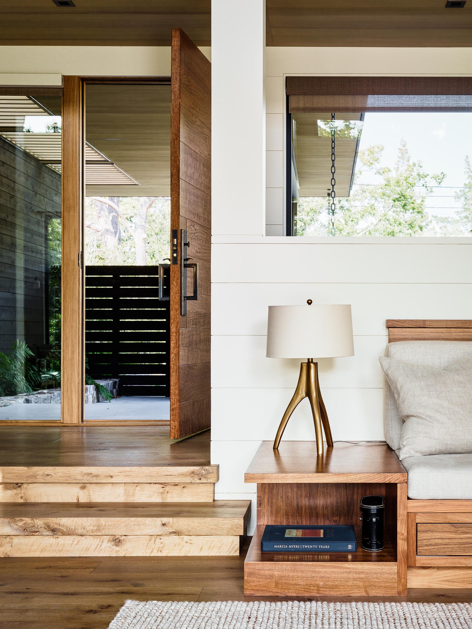 A bright interior with wood front door, wood flooring, and wood sofa frame.