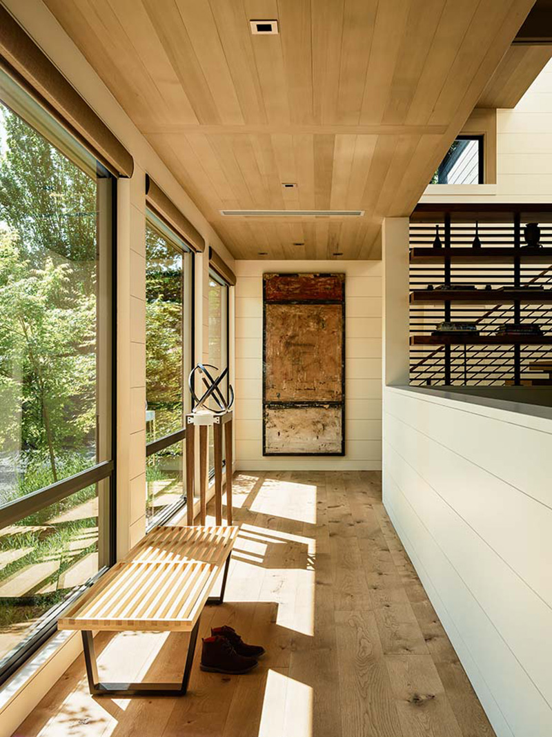 A modern hallway with wood floor, wood ceiling, and tall windows.