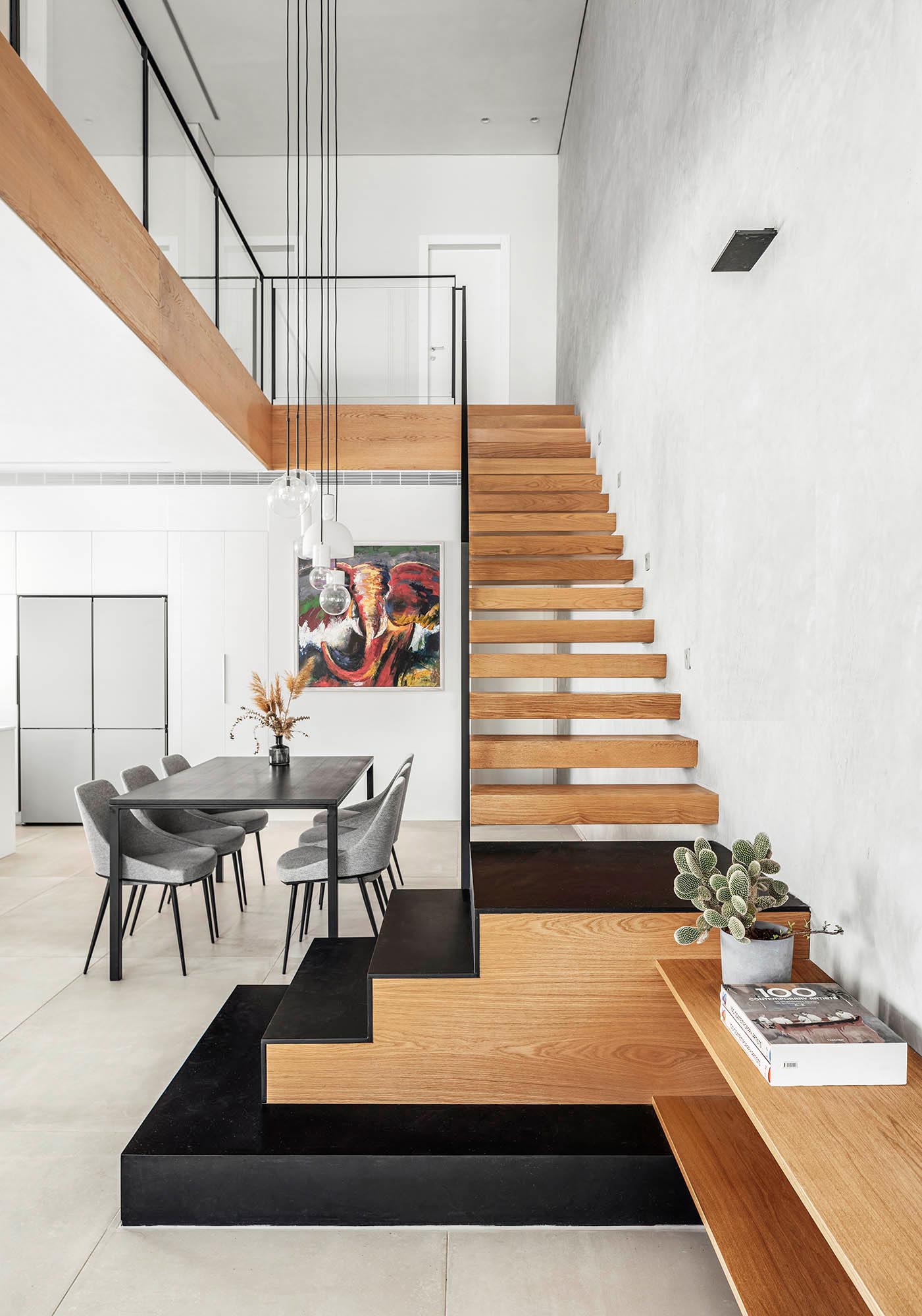 A floating oak staircase connects the various levels of this modern home, incorporates black iron stairs at the bottom, and transitions to become the TV sideboard in the living room.