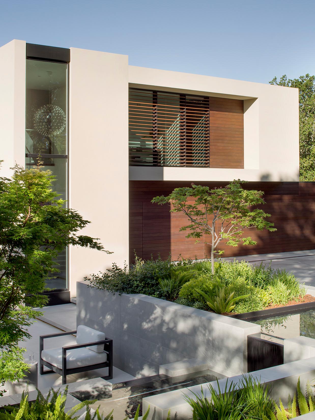 Much of the landscape around this modern house has been left to its natural state, however some areas have been updated to include water features, retaining walls, pathways, and small sitting areas.