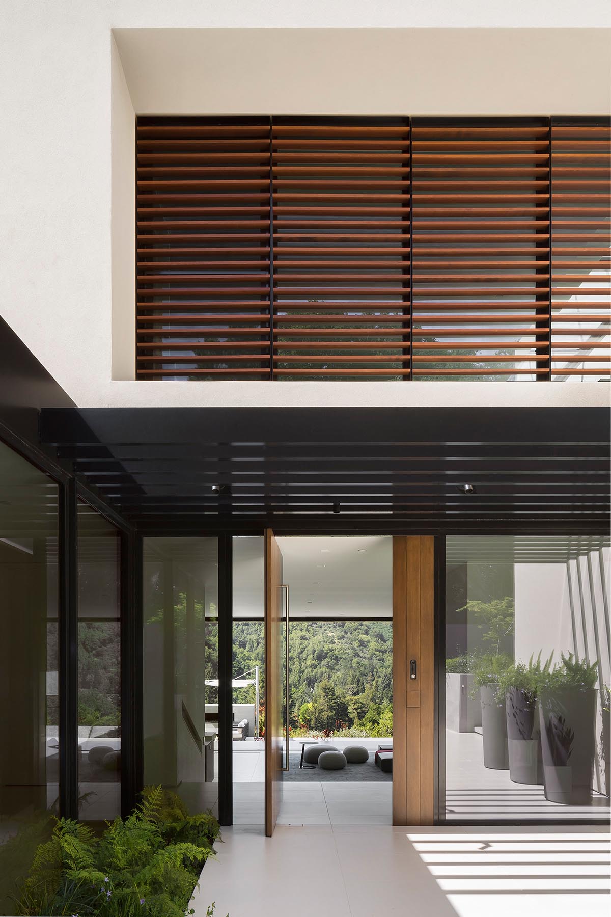 Upon arrival at this modern house, a sunken entry courtyard guides visitors to the oversized pivoting wood front door.