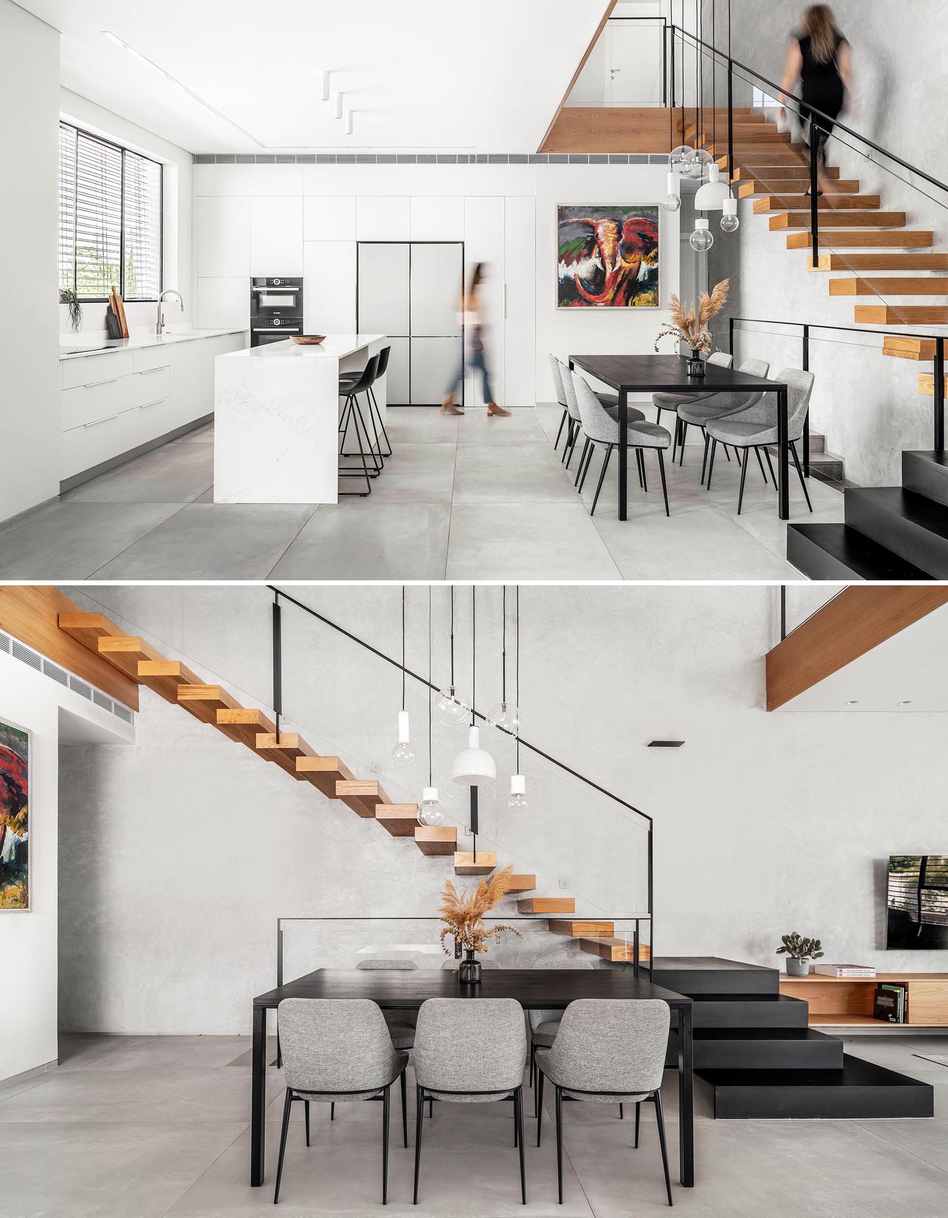 This modern dining room is furnished with a black table and light gray chairs, while white minimalist cabinets and drawers line the walls in the kitchen.