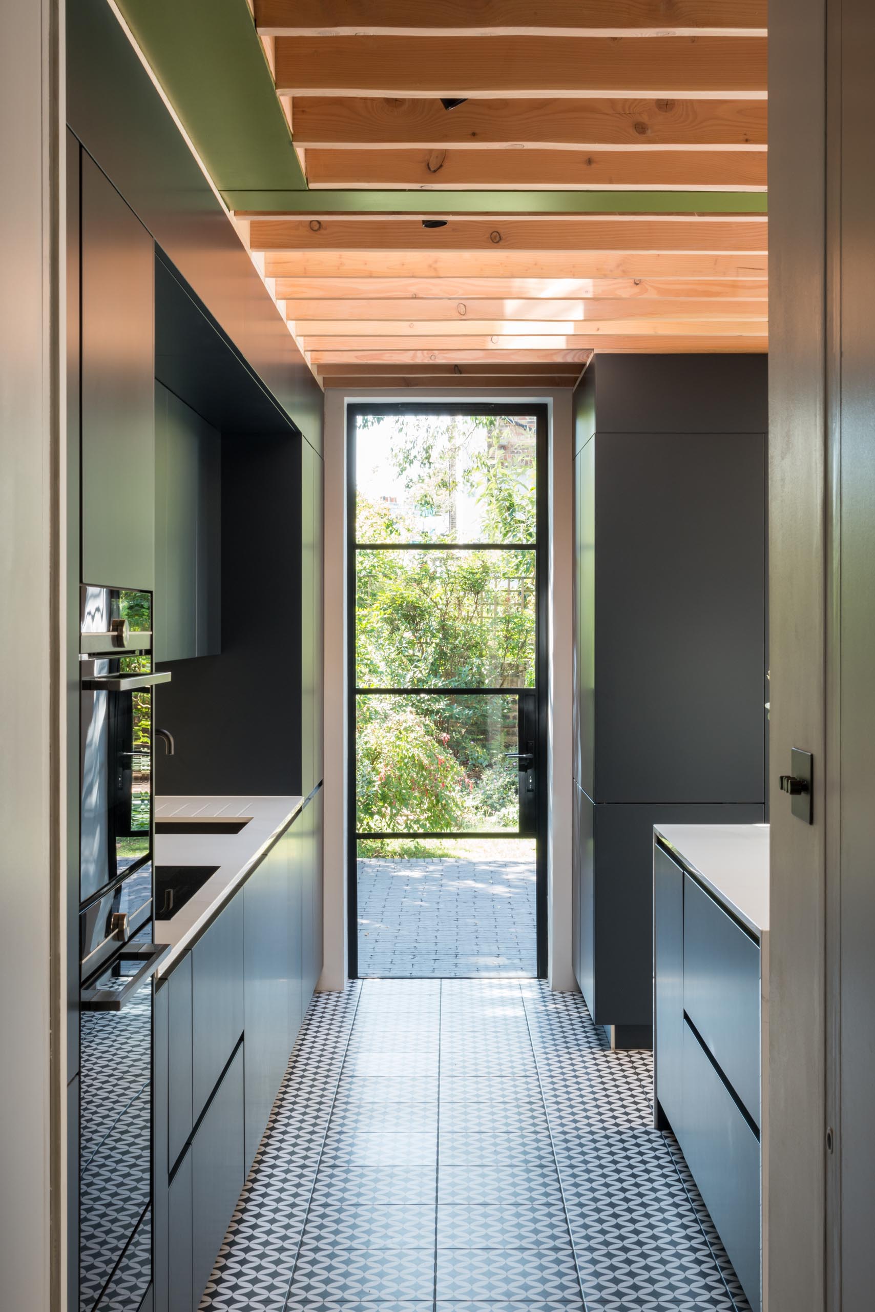 Minimalist matte black cabinets in this modern kitchen contrast the white countertops, while the patterned floor tile adds an artistic touch. 