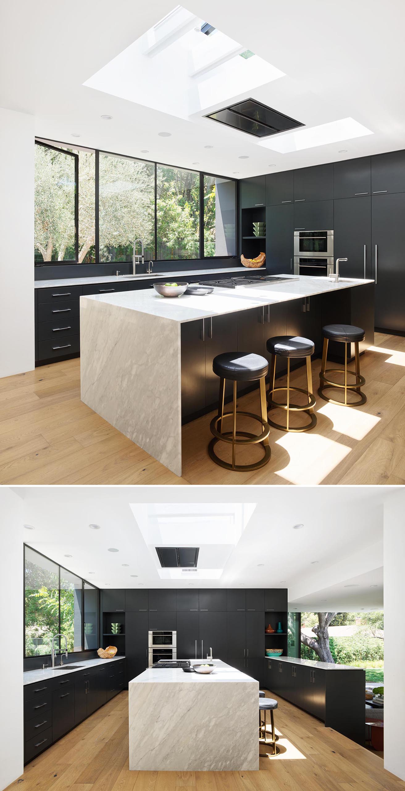 A modern kitchen with skylights, and Calcutta Cream marble countertops that contrast the matte black cabinets.
