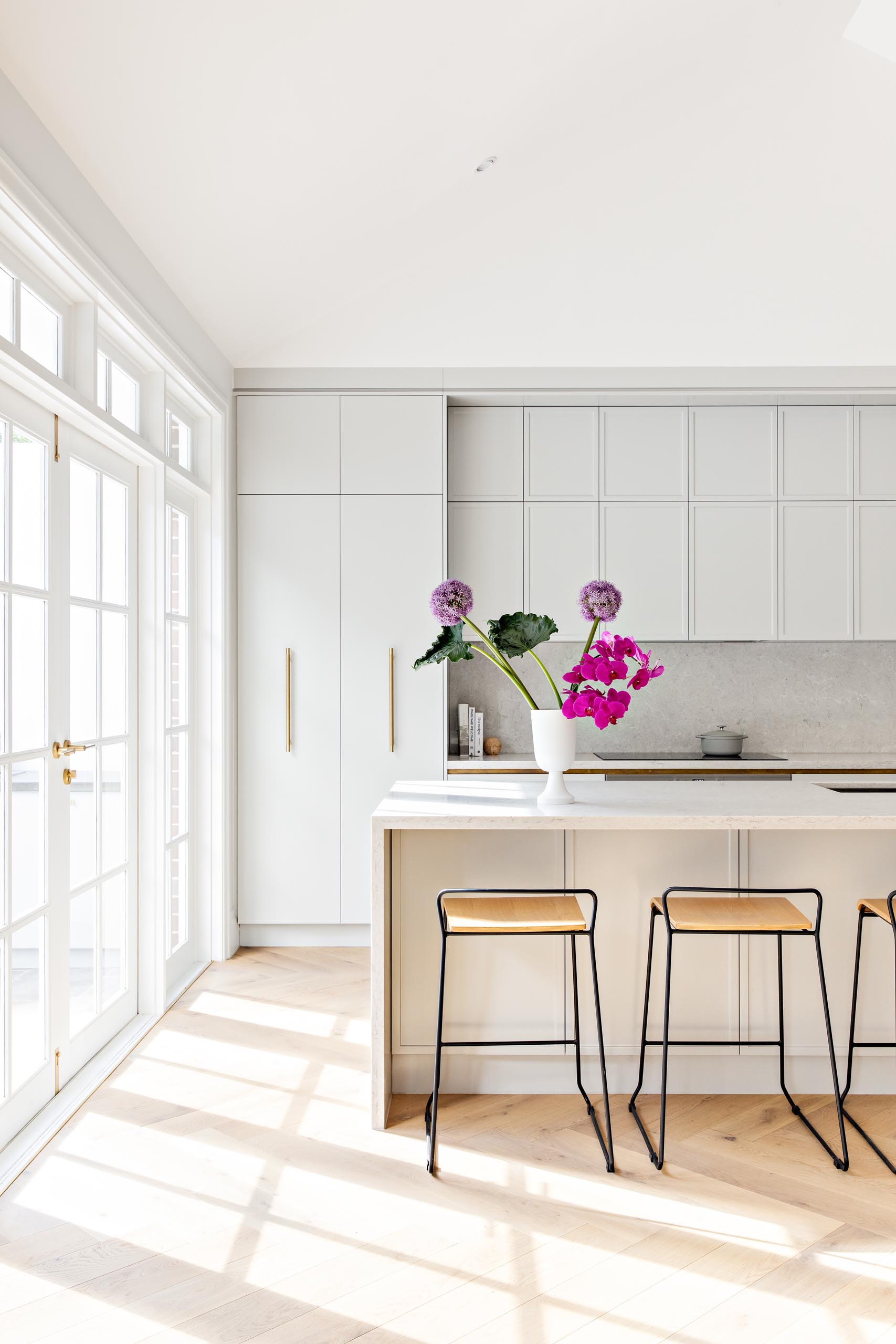 A modern kitchen with light grey cabinets and light stone countertops.