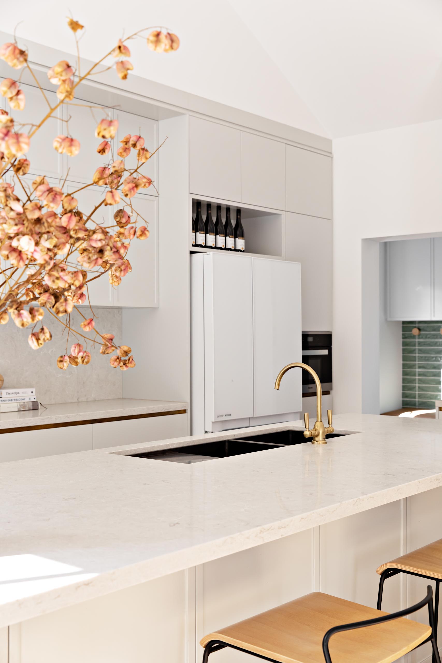 A modern kitchen with light grey cabinets, a long island, and light stone countertops.