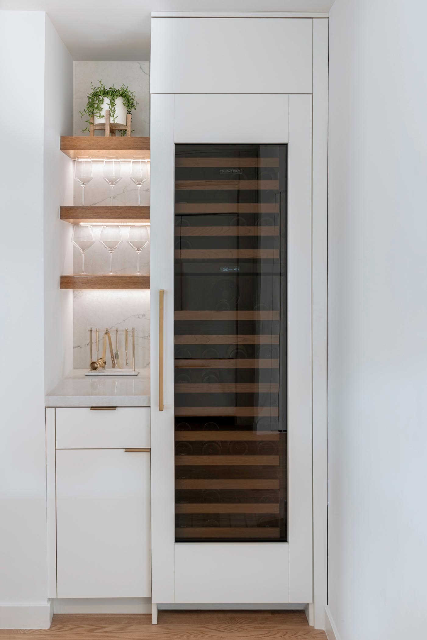 A built-in wine fridge and a small custom designed bar with storage and floating shelves with hidden lighting.