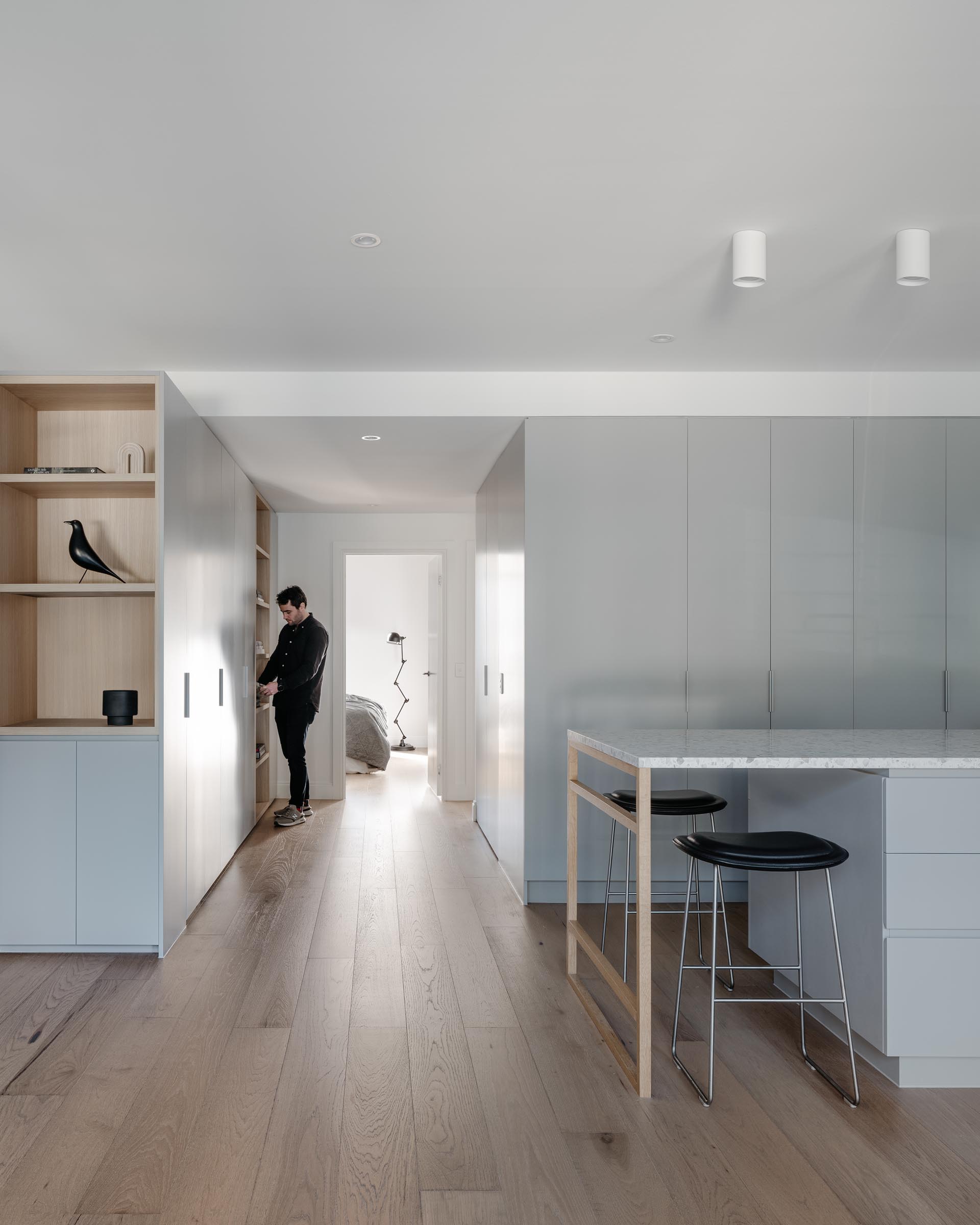 A modern apartment with minimalist light gray cabinets and oak flooring.