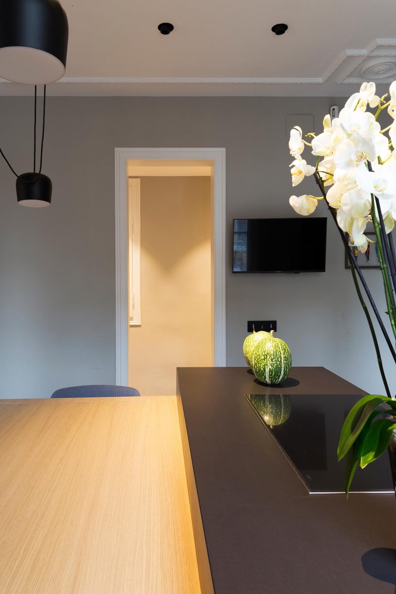 A modern dark kitchen island contrasts a wood dining table.