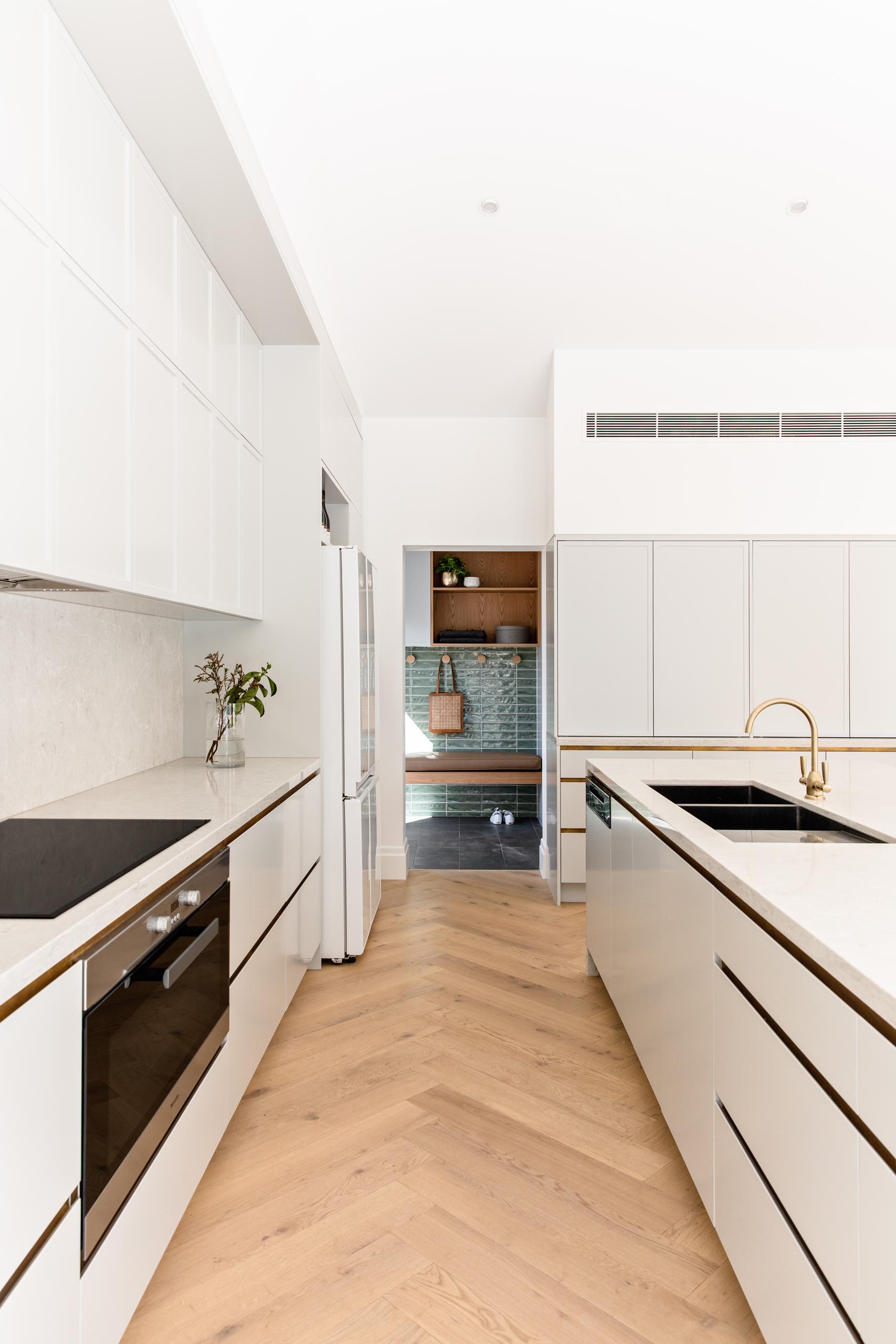 A modern kitchen with light grey cabinets, a long island, and light stone countertops.