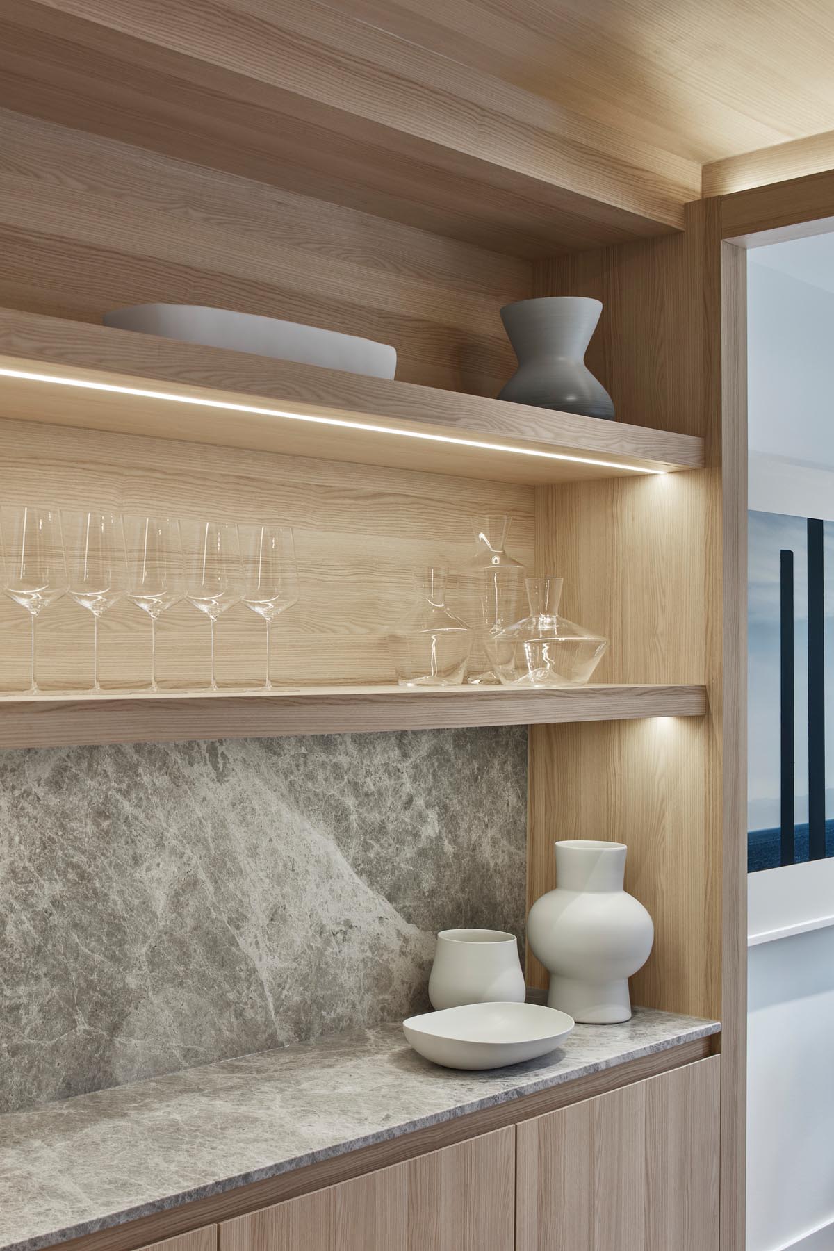 A modern wood kitchen with hidden lighting to show off the items on the shelf below.