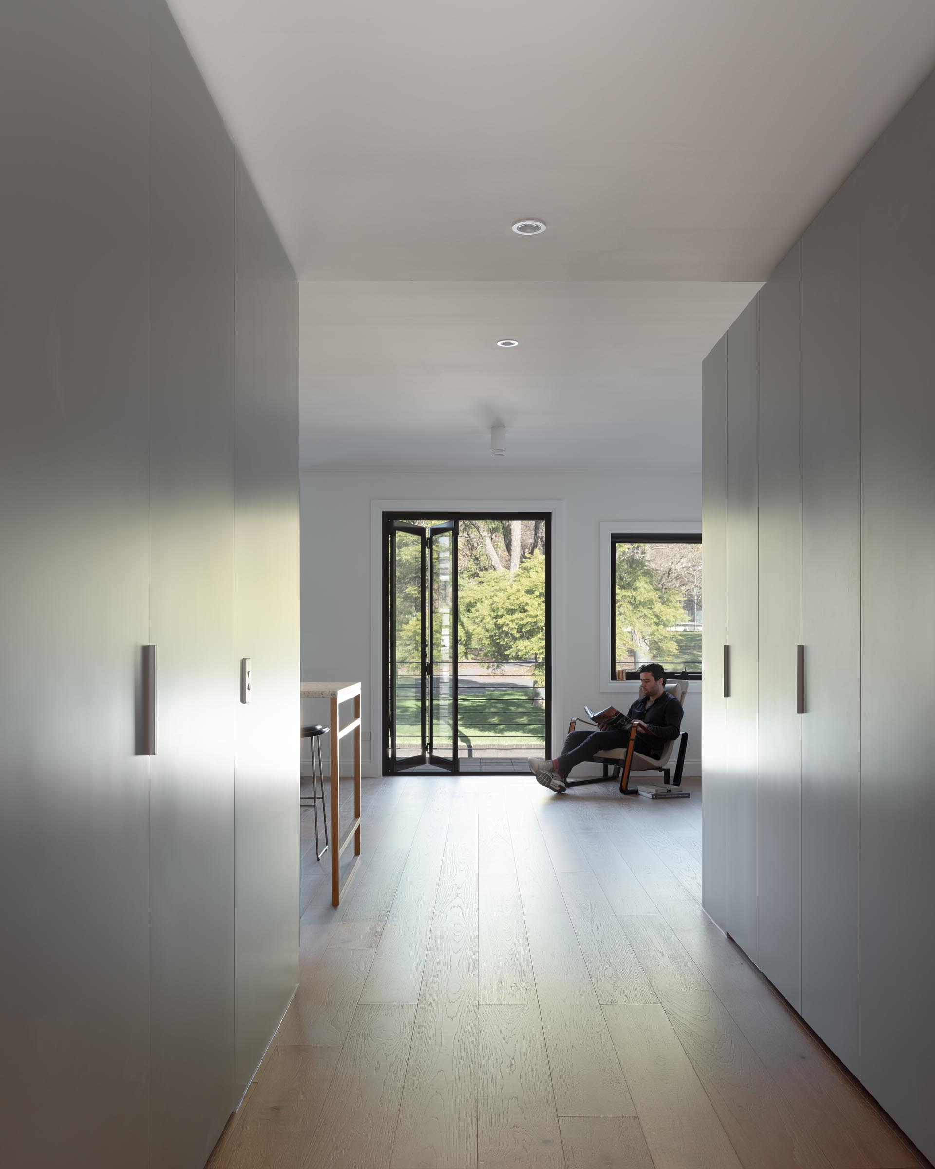 A modern apartment with minimalist light gray cabinets and oak flooring.