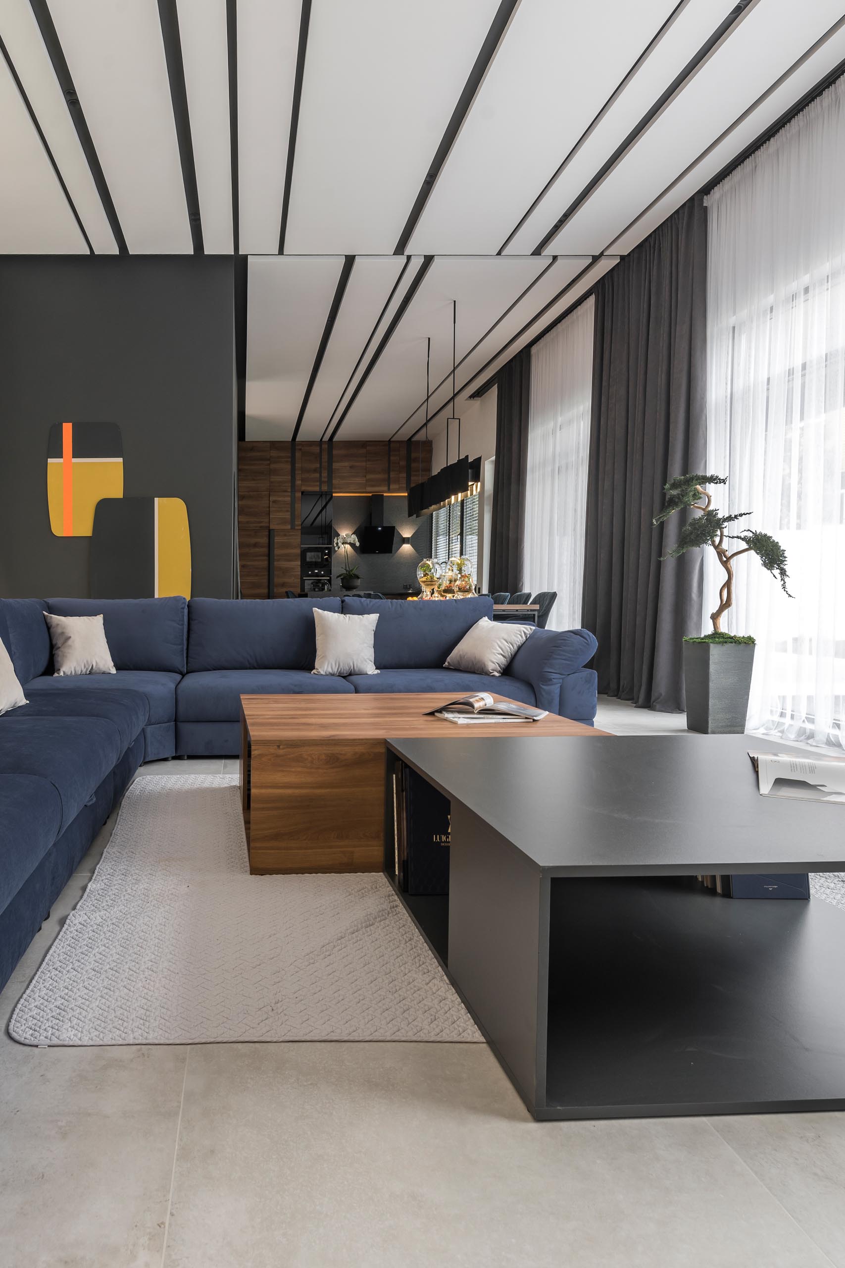 A modern living room with a large blue sofa, and a wood and gray coffee table.