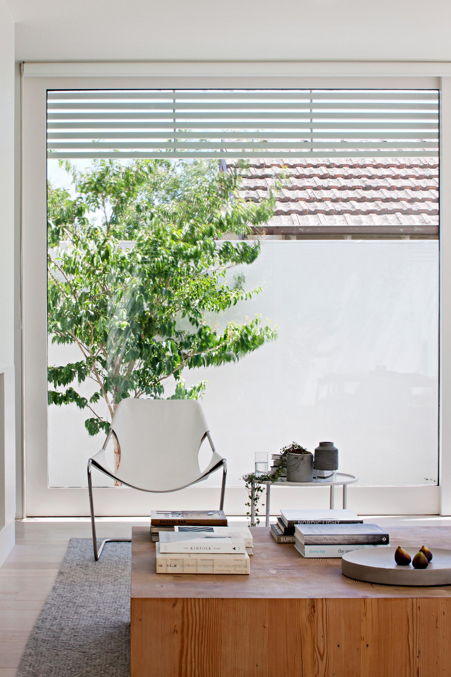 A modern living room with a wood coffee table and large windows.