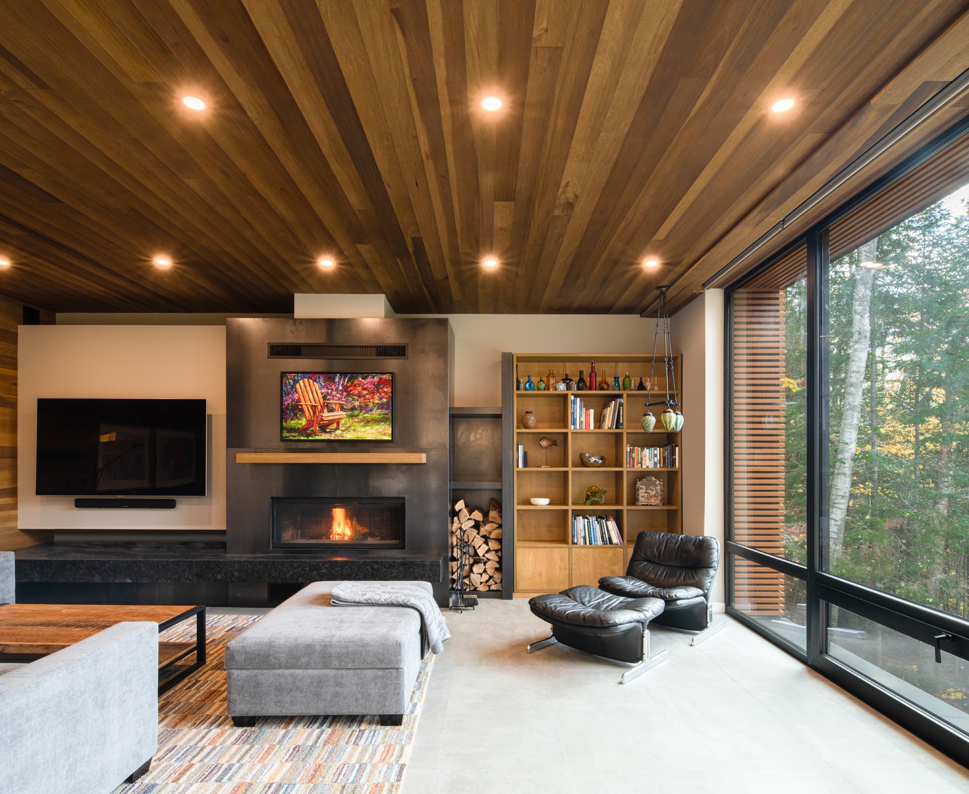 Inside his prefab home, wood has been used to create a space that's warm and welcoming. In the living room, there's a fireplace, a dedicated area for the television, and a bookcase.