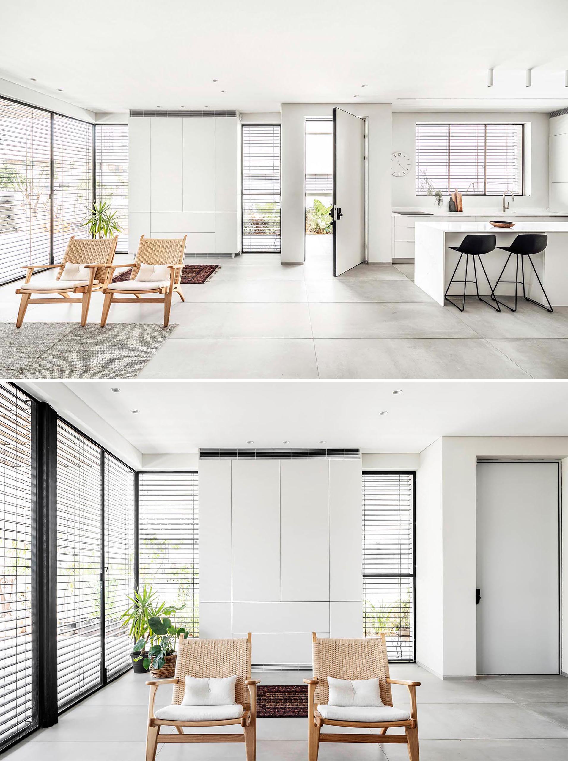 Tall windows line the walls of this modern interior and let in copious amounts of natural light into the open living room, dining area, and kitchen.