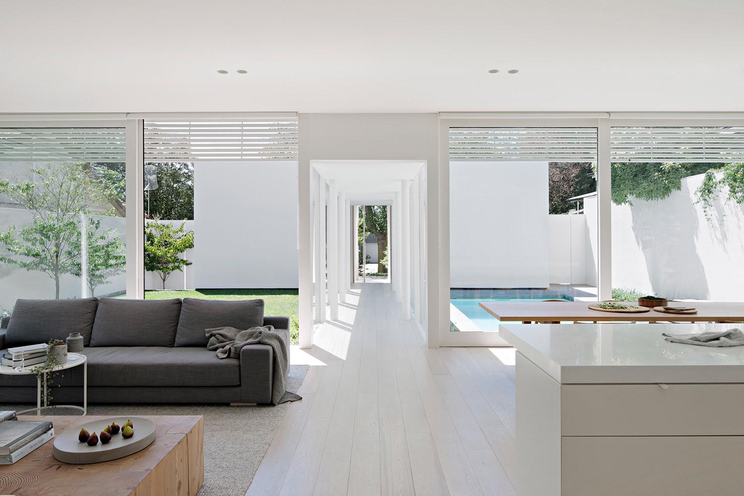 A modern open plan interior with large windows, light floors, and white walls.