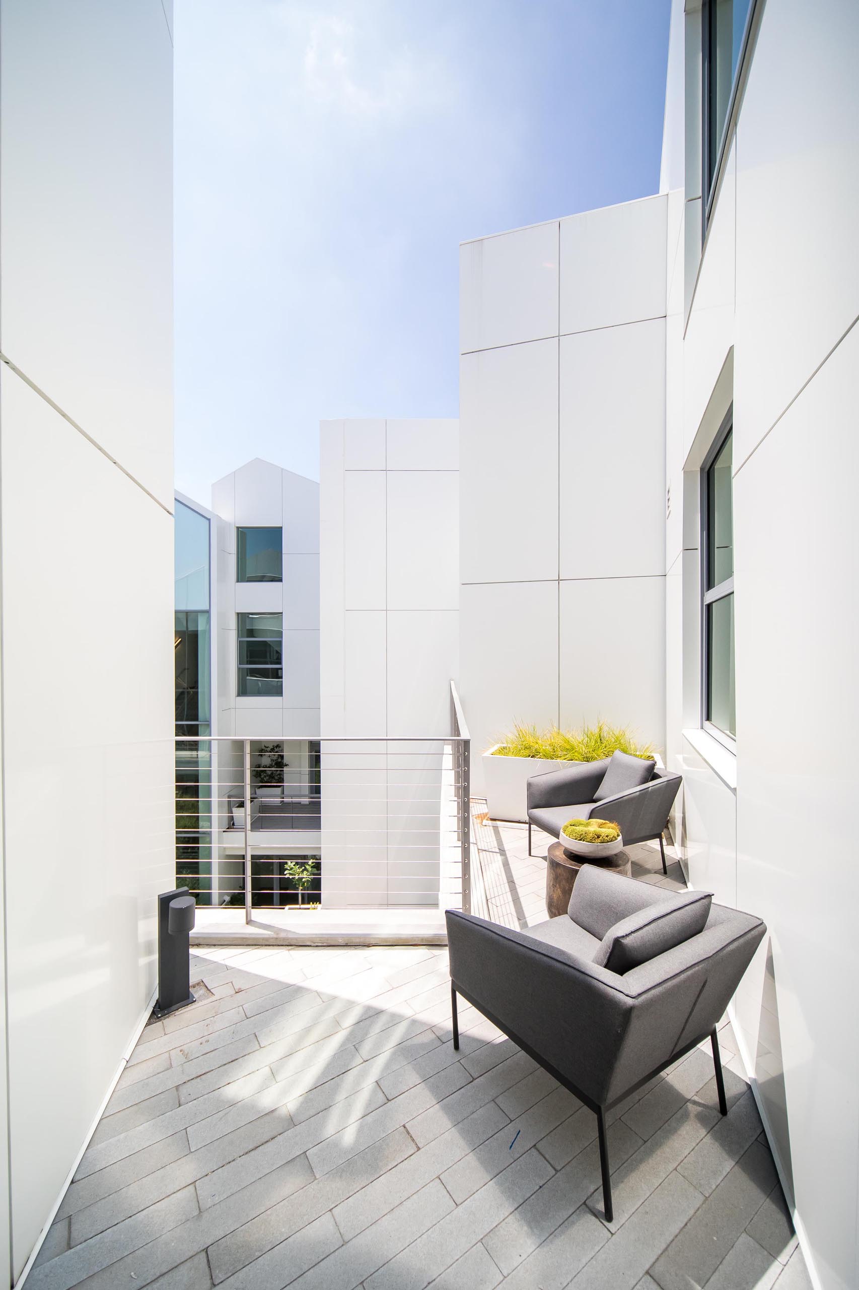 A small terrace with a pair of armchairs and a planter.