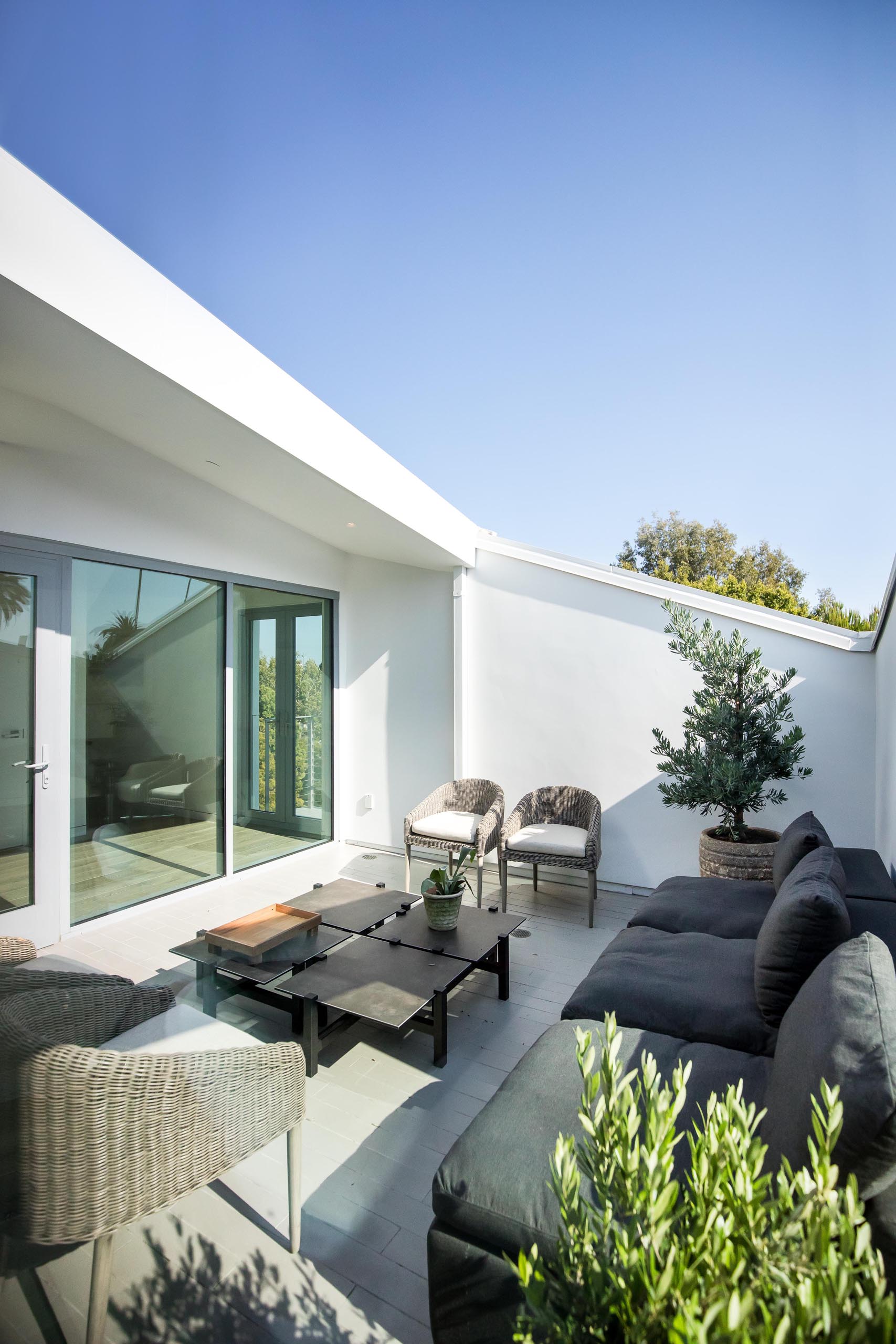 A modern terrace with a sofa, coffee table, and armchairs.