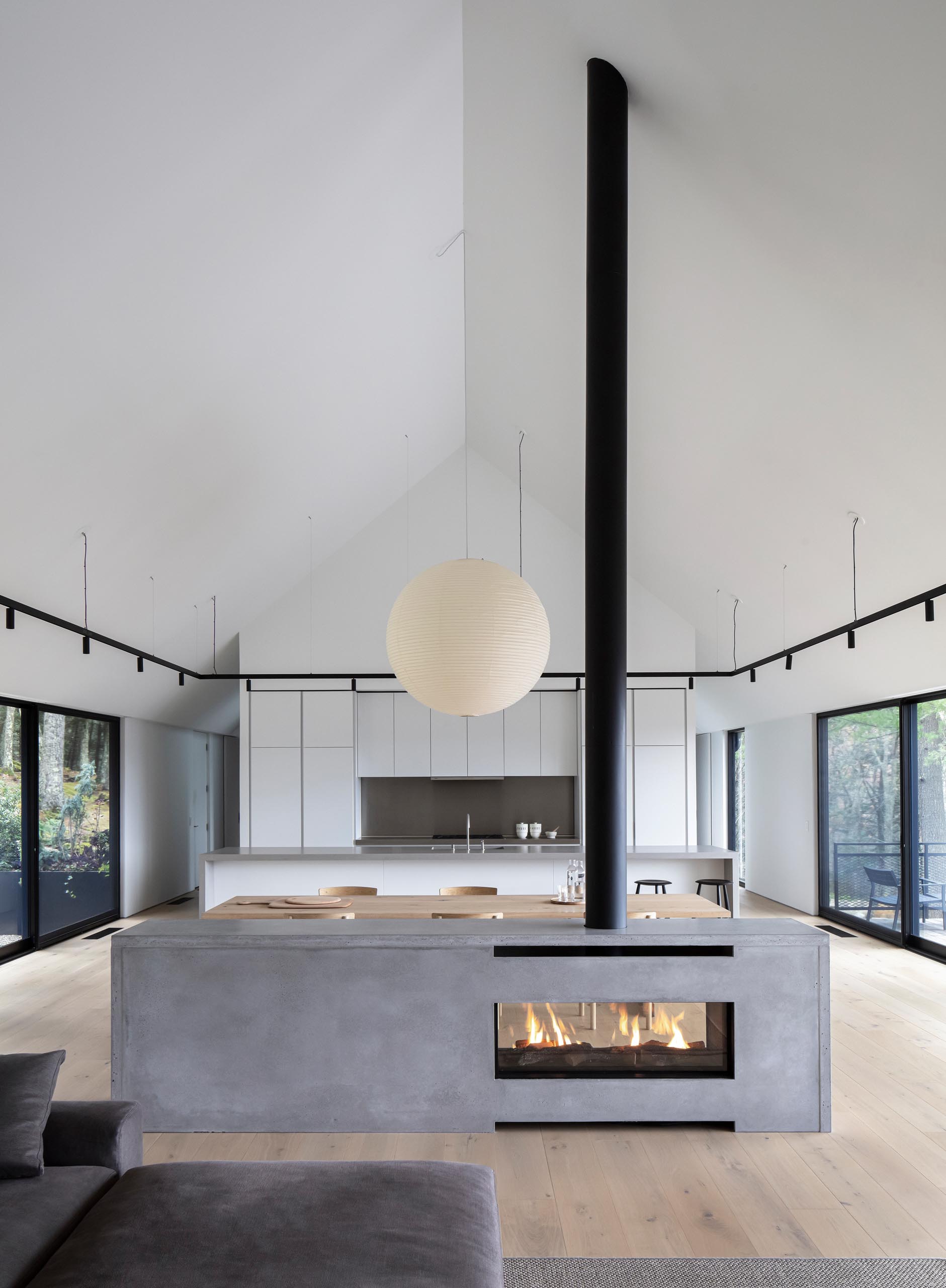 A modern house interior with a see-through fireplace with a concrete surround.