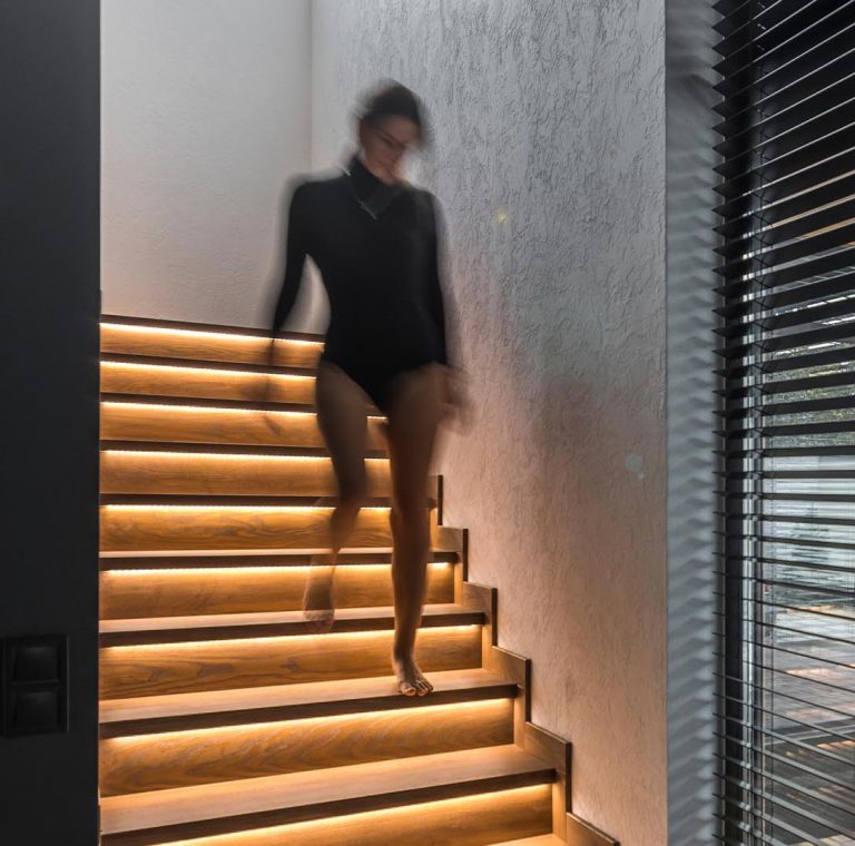 A Strip Of LED Lights Under The Stairs Of This Home Adds A Warm Glow To The Interior