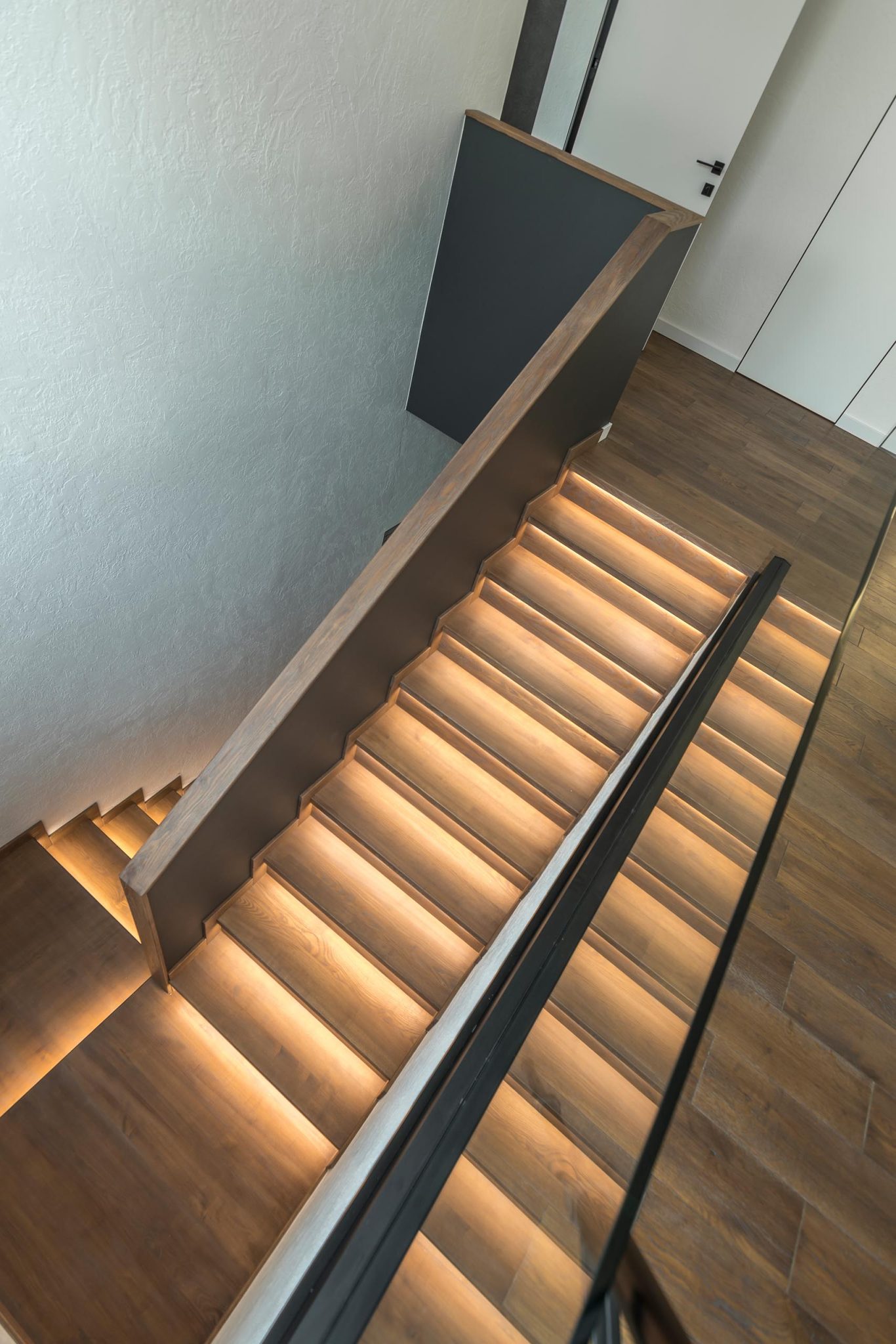 A Strip Of LED Lights Under The Stairs Of This Home Adds A Warm Glow To