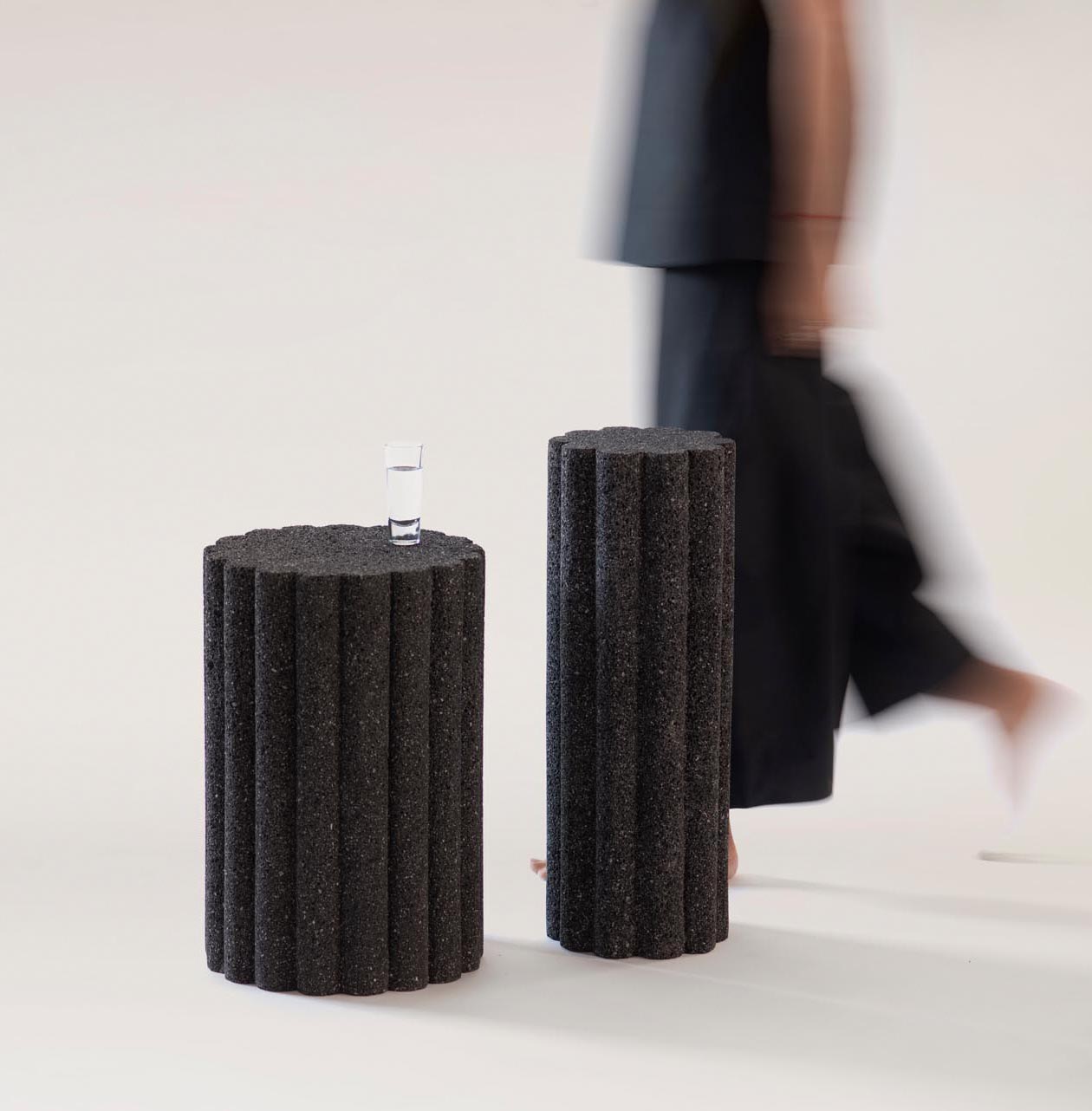 A collection of modern black side tables and stools made from volcanic rock.