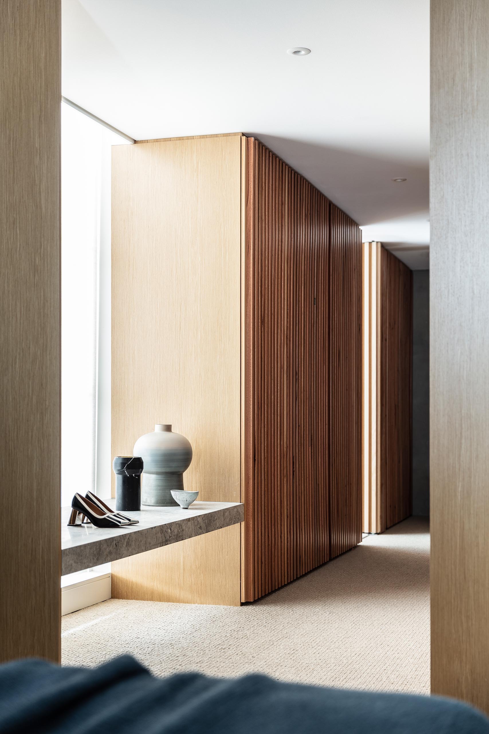 This modern walk-in closet has plenty of storage for clothes, and also includes a stone bench by the window.