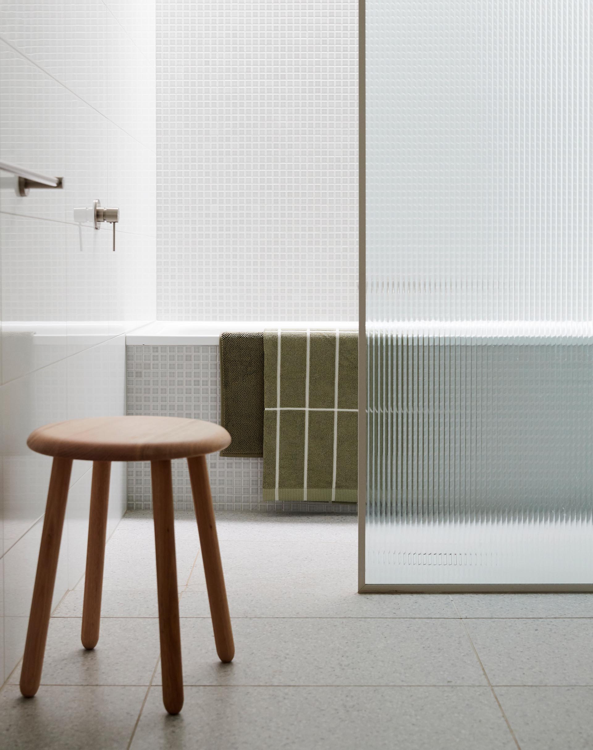 In this modern bathroom, small square tiles cover the wall and the exterior of the bath.