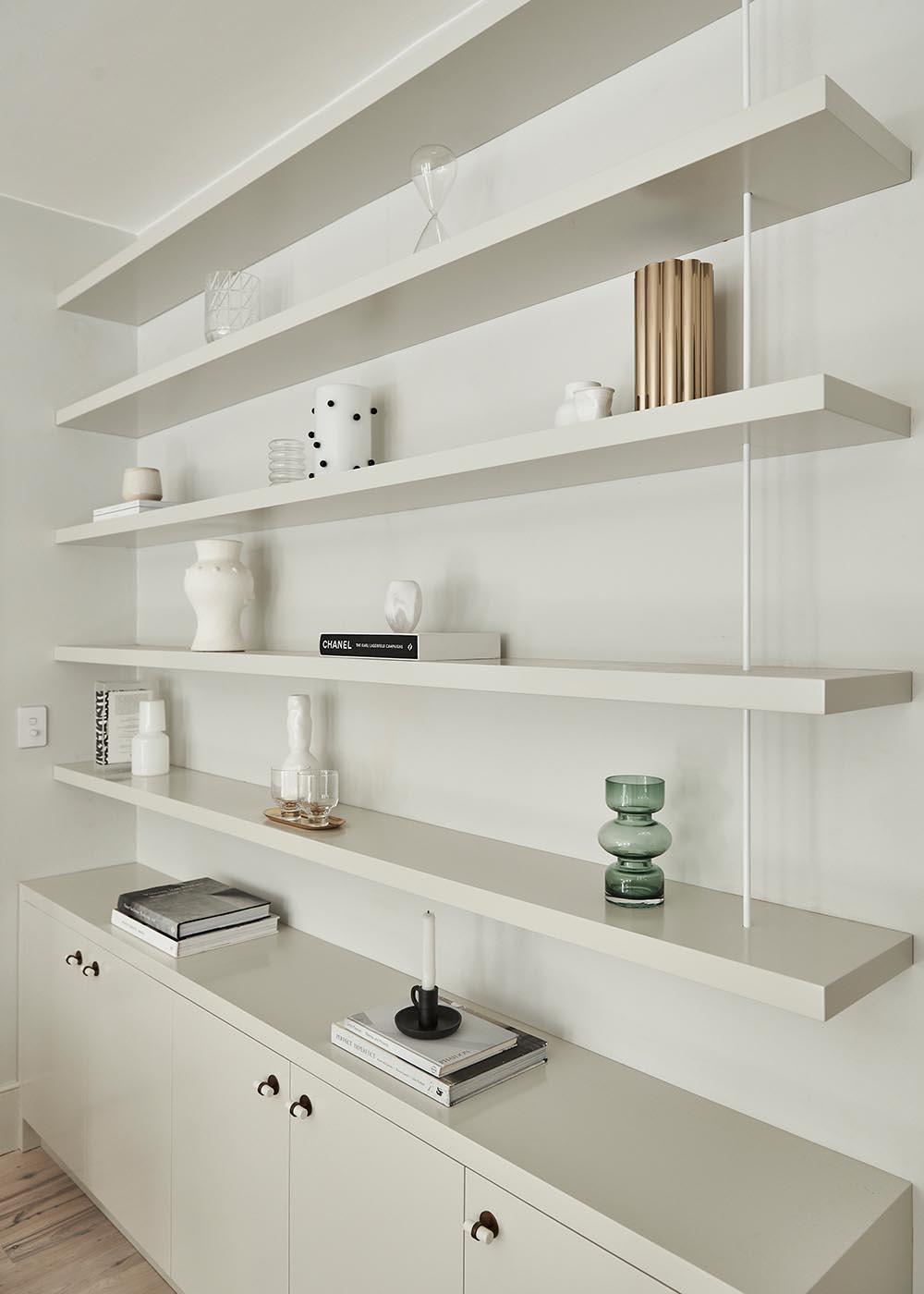 Custom cabinetry and wall shelving almost seamlessly blend into the wall, allowing the decorative objects to stand out.