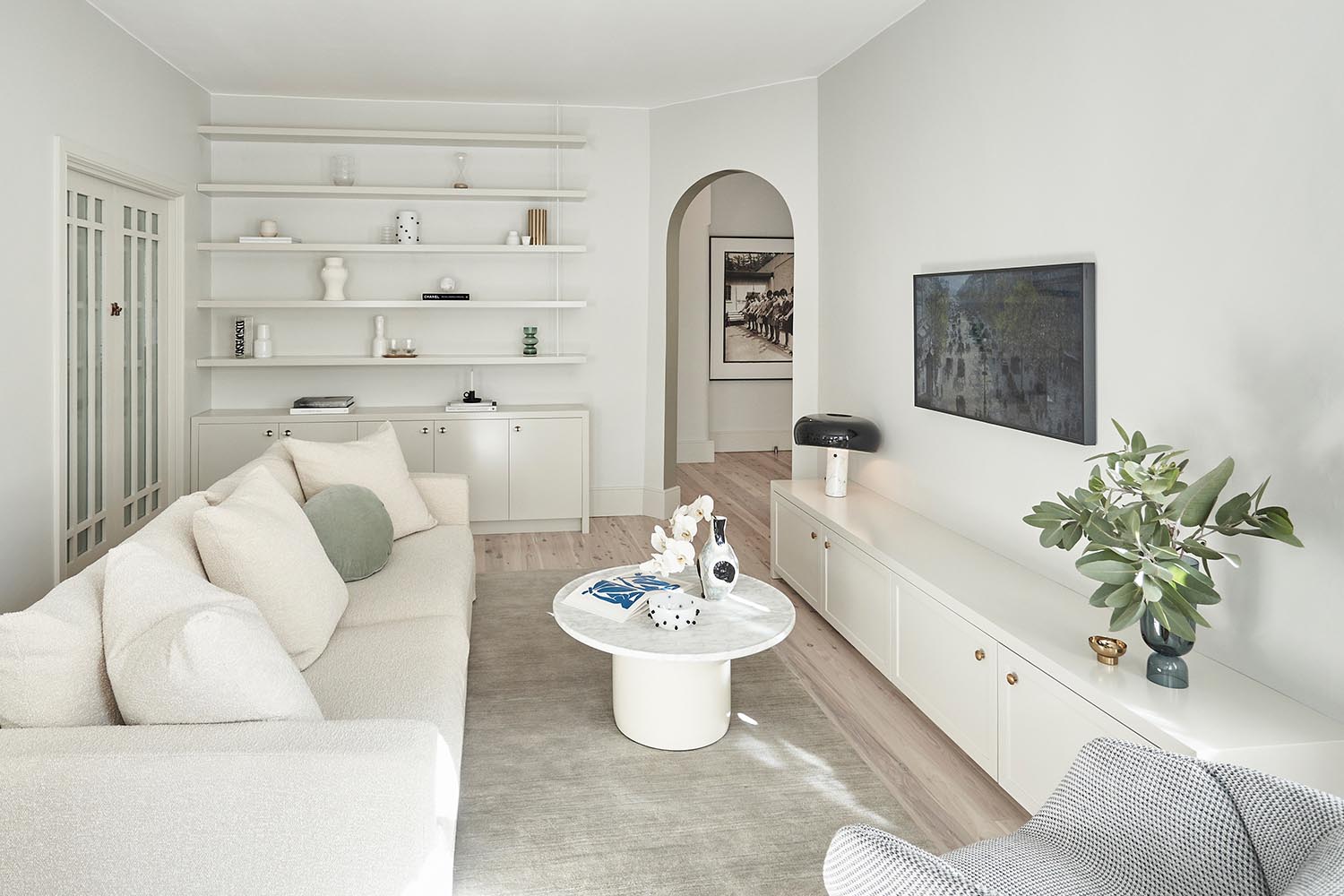 A white living room with custom cabinets and shelving.