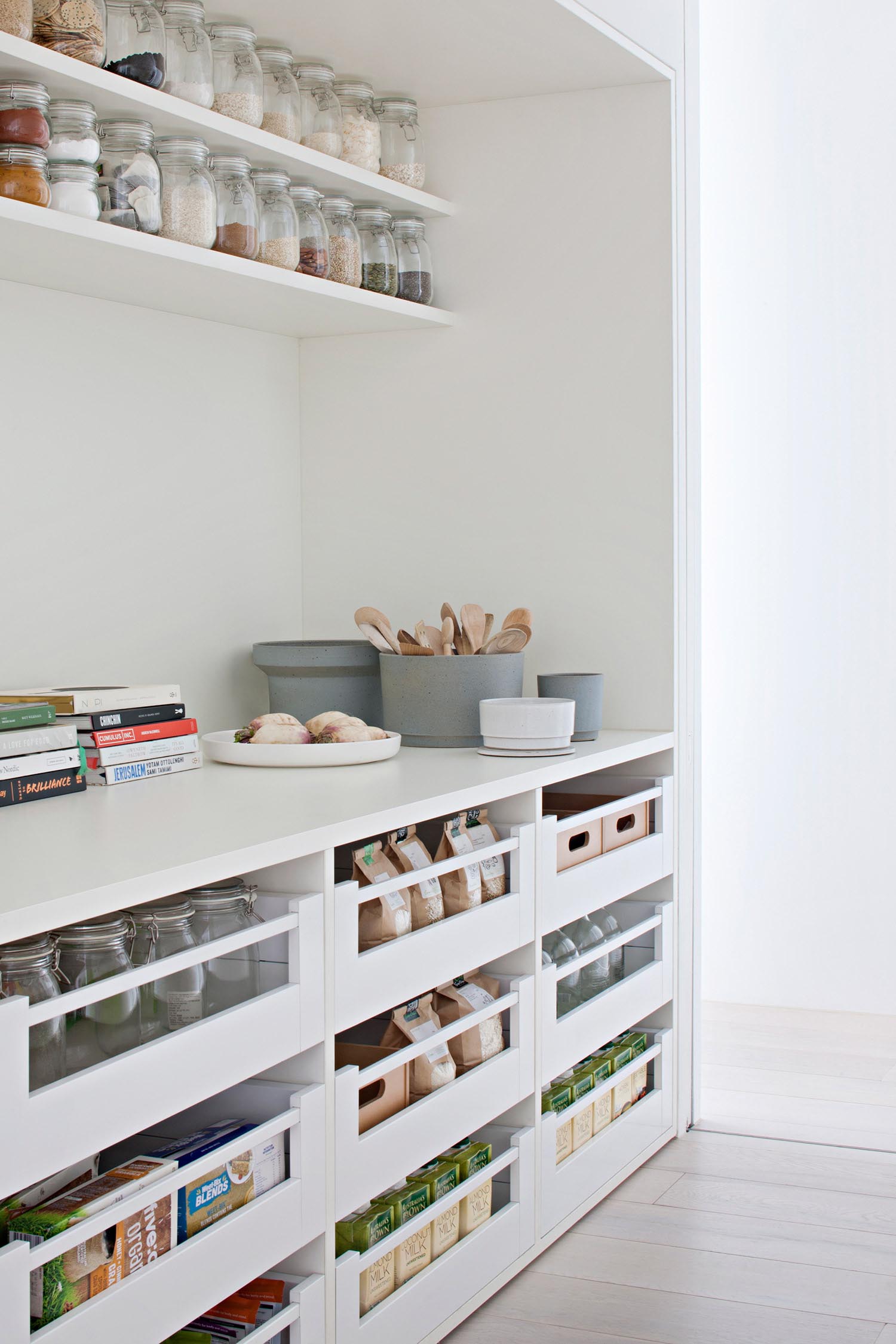 A modern white pantry with open shelves and drawers.