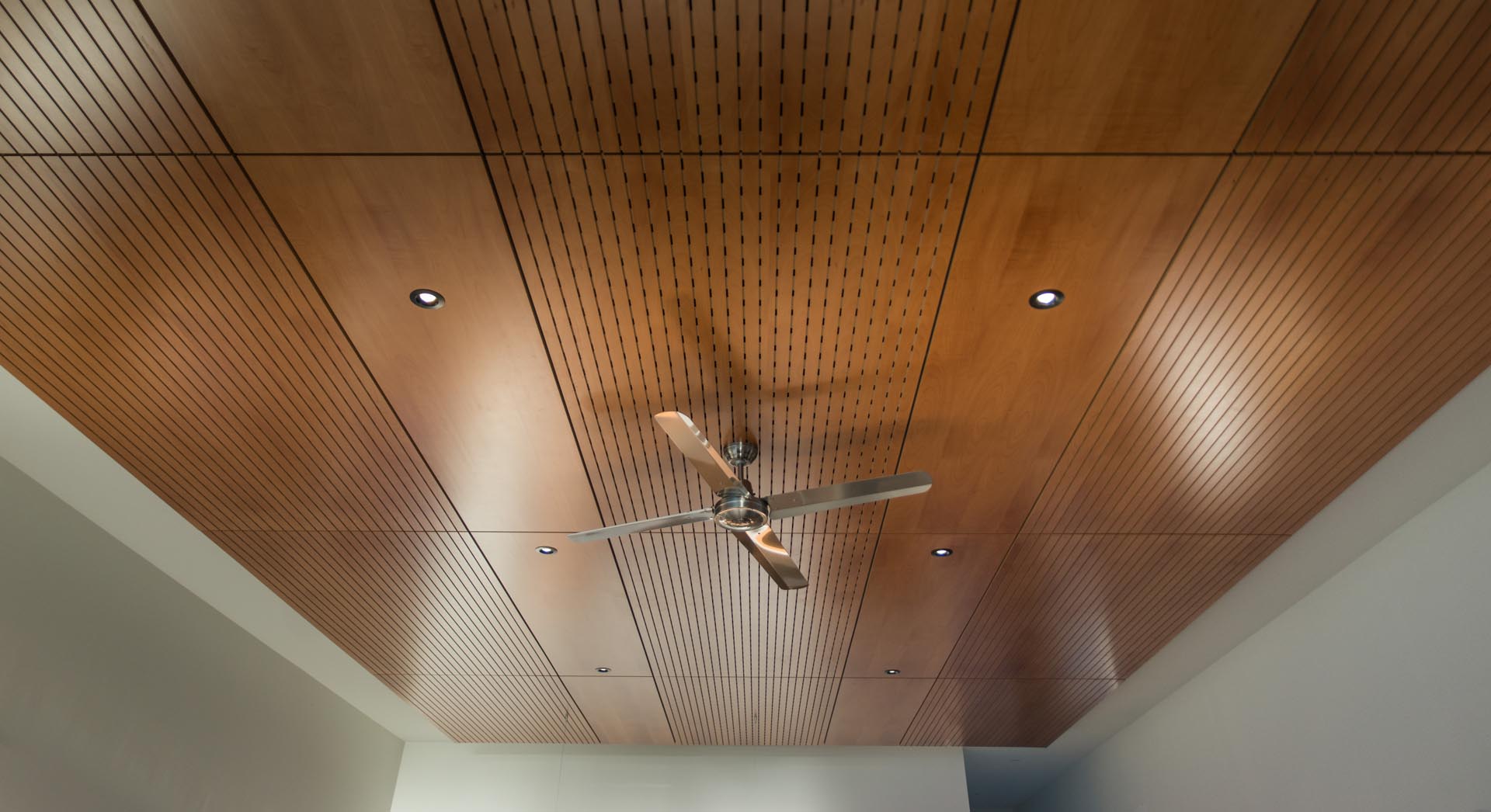 An open plan interior with a wood ceiling accent and hidden lighting.