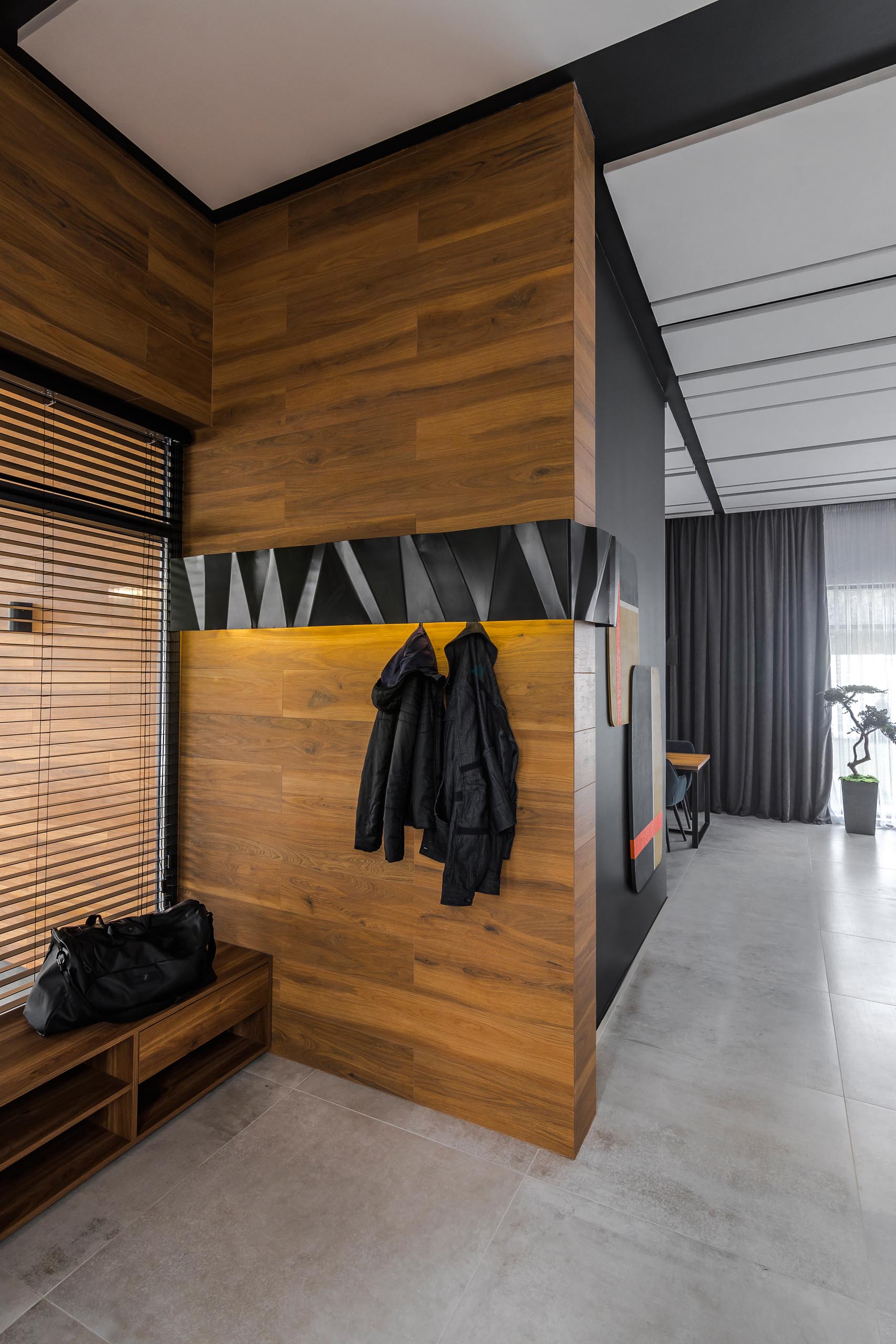 A modern wood entryway with a black metal accent that has hidden hooks and lighting.