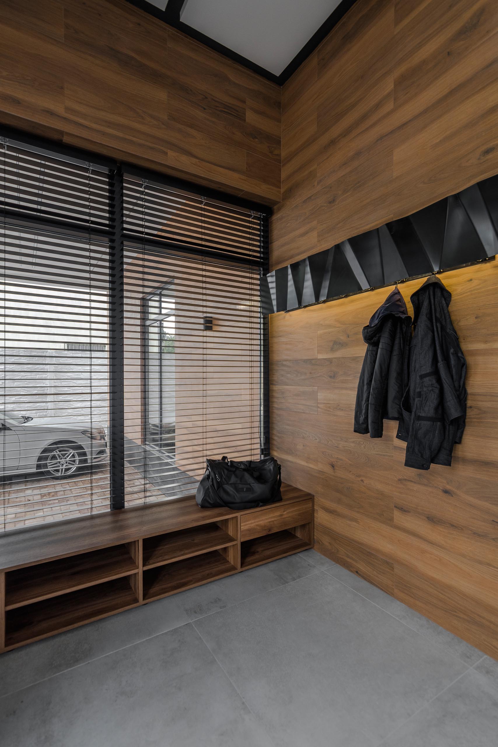 A modern wood entryway with a black metal accent that has hidden hooks.