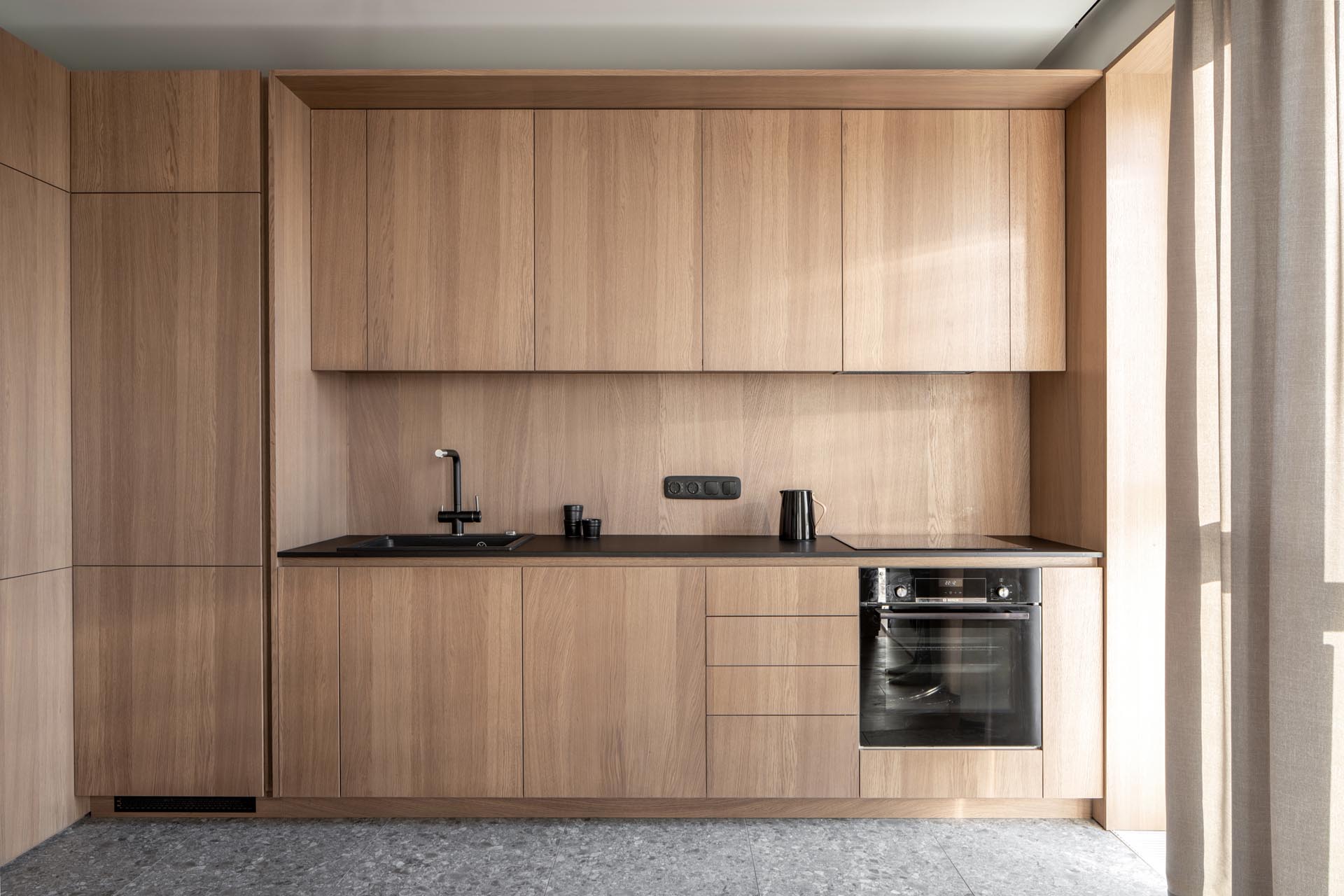 A modern wood kitchen with hardware-free cabinets, and an integrated fridge and dishwasher.