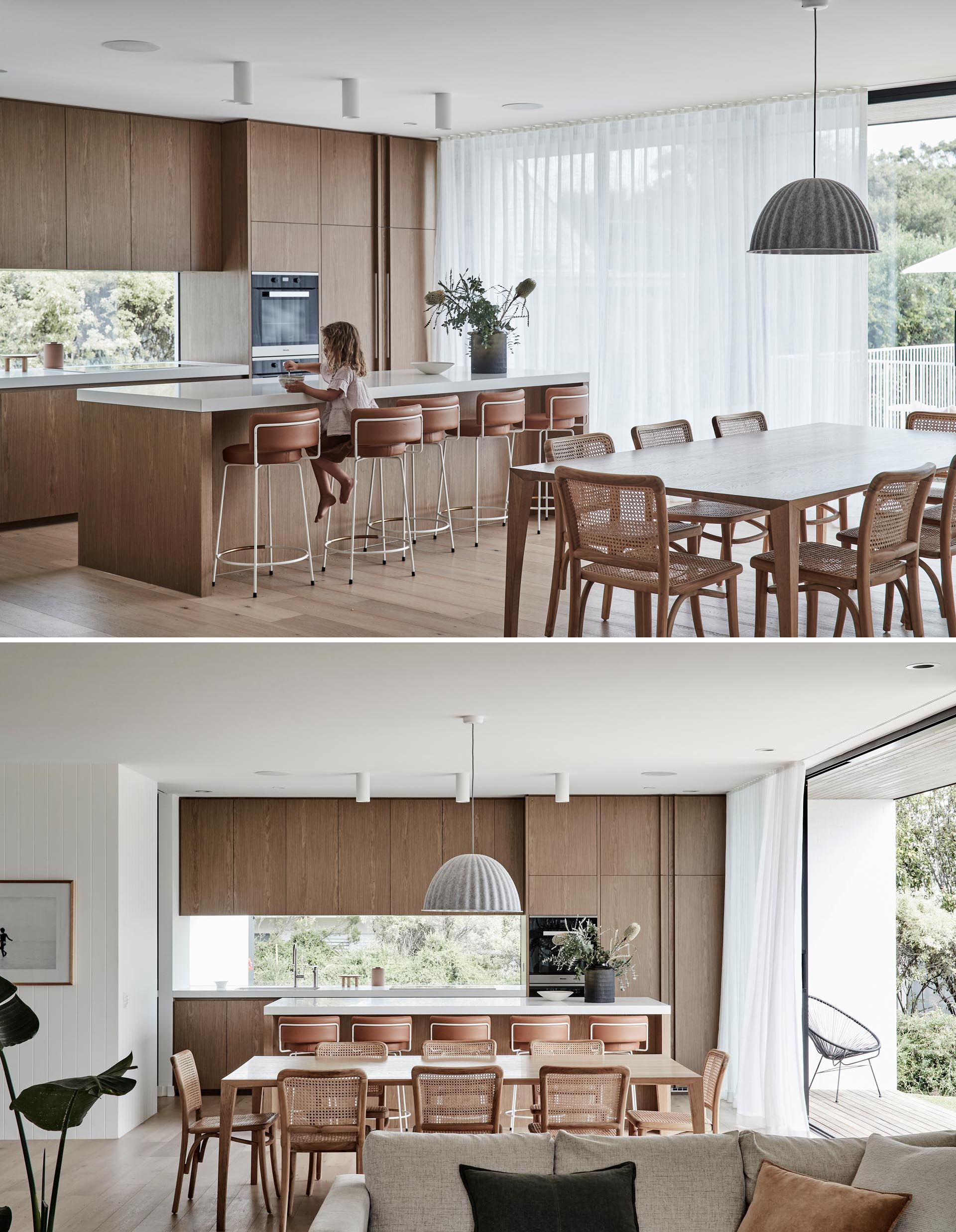 Warm wood dining chairs and kitchen cabinets add a natural element to the interior design of this modern home, while light brown leather stools provide seating at the island.