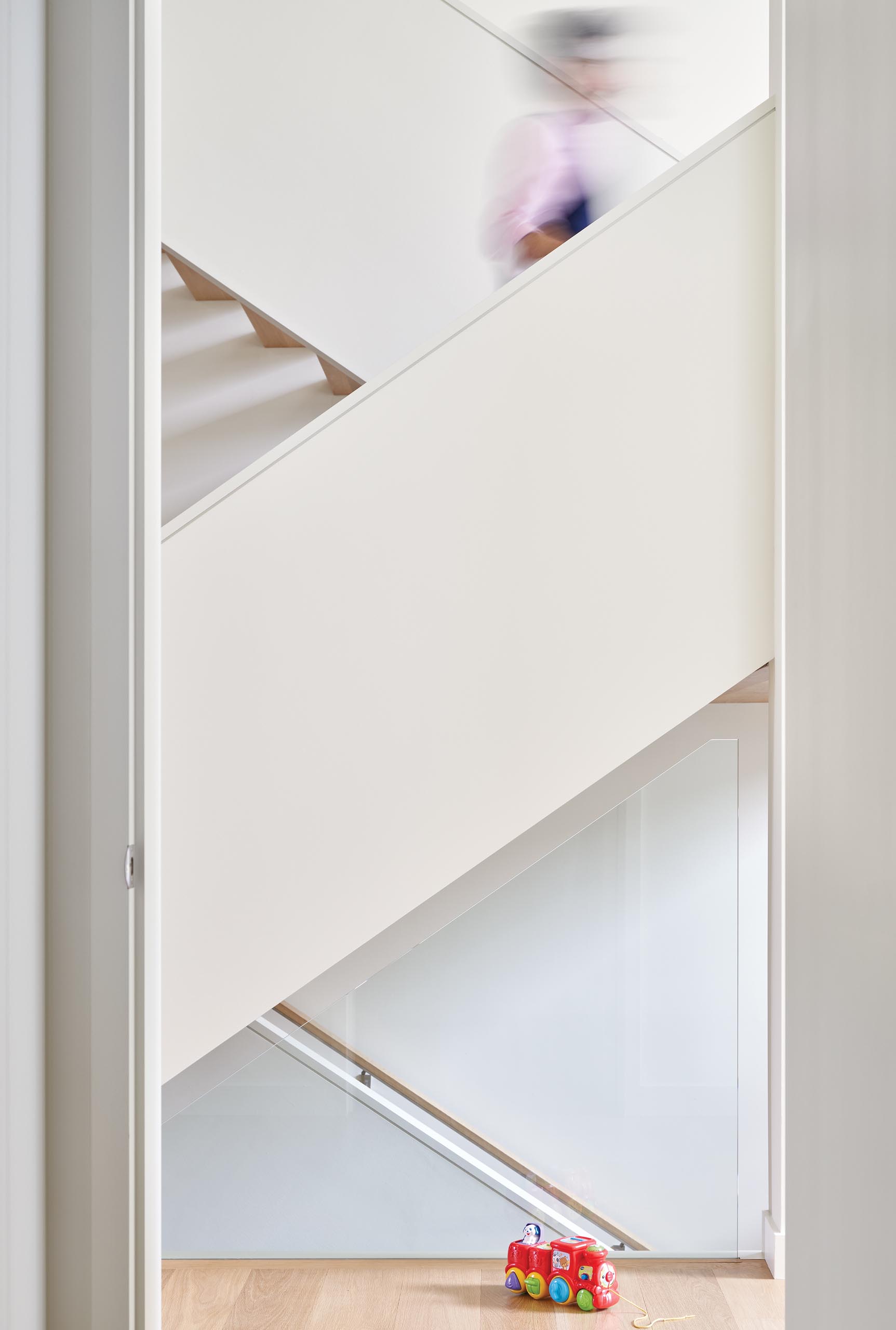 A modern house with an open wood staircase with glass railings that connects the multiple levels of the home.