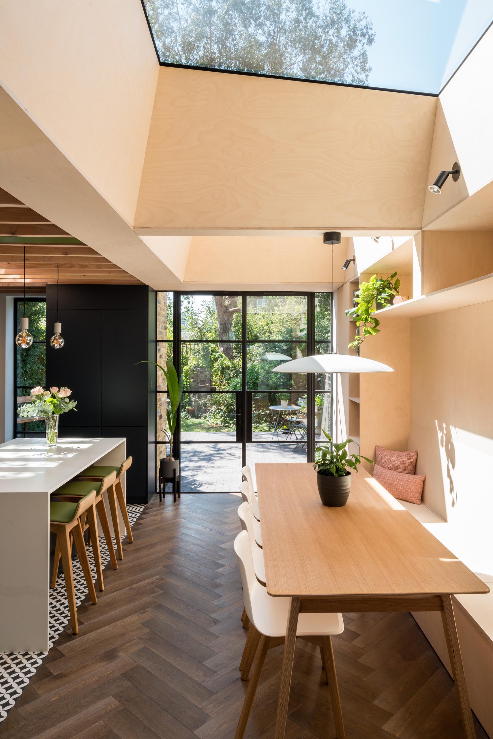 A new dining room has been designed with fitted storage and a long bespoke dining bench, Crittall doors, and two skylights.